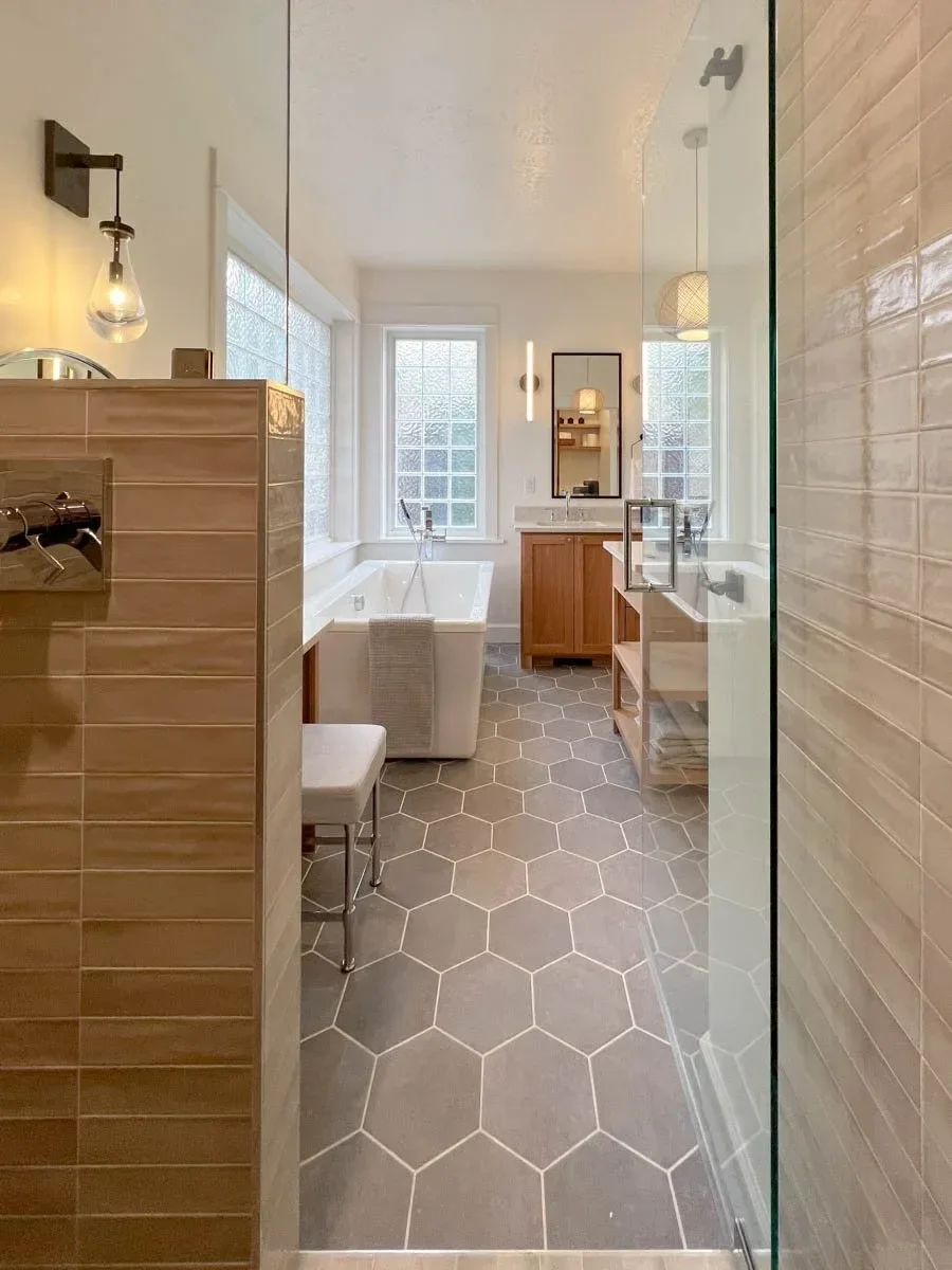 Modern home renovation featuring warm wood cabinetry, hex tile flooring, textured shower walls, and neutral-toned interiors in Southern Oregon, completed by Verity Construction.
