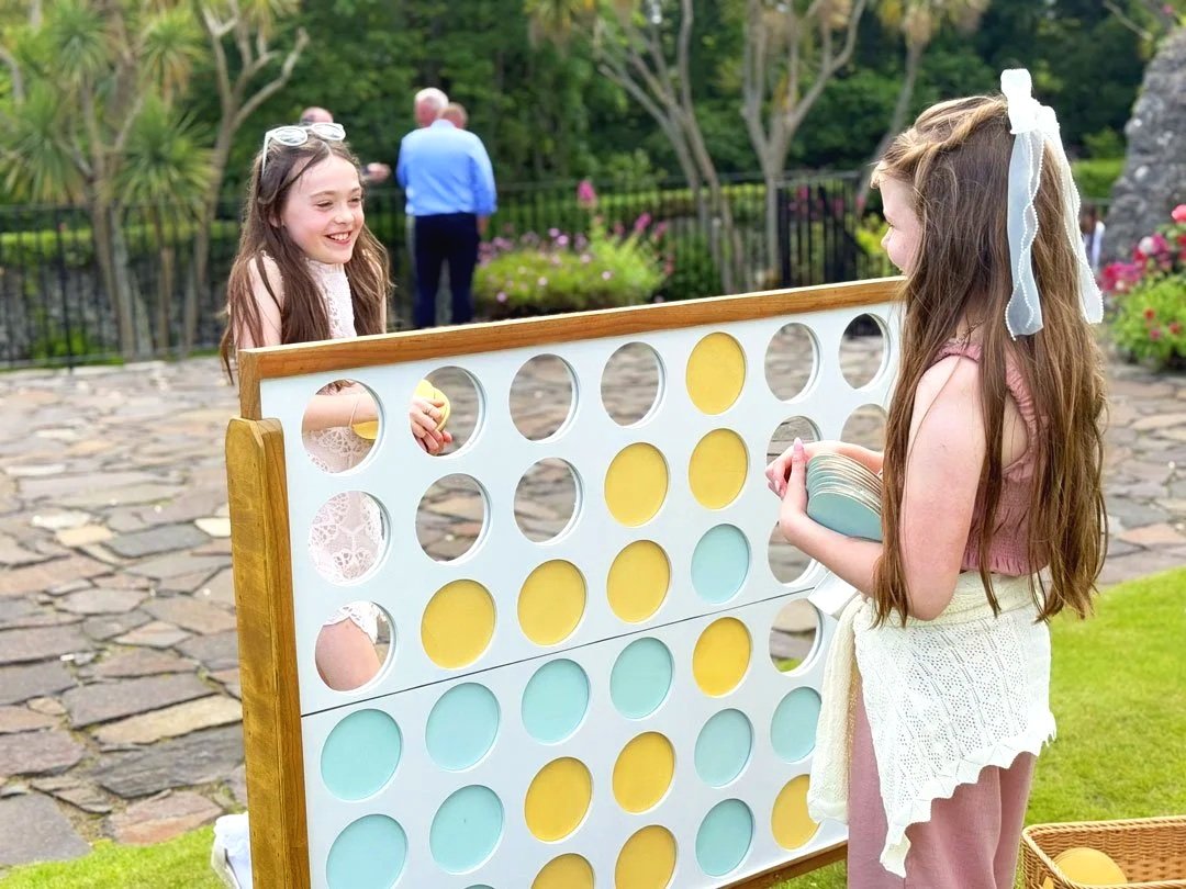 Wooden Giant Connect 4 Lawn Game with a wicker basket containing Yellow & Mint coloured counters.