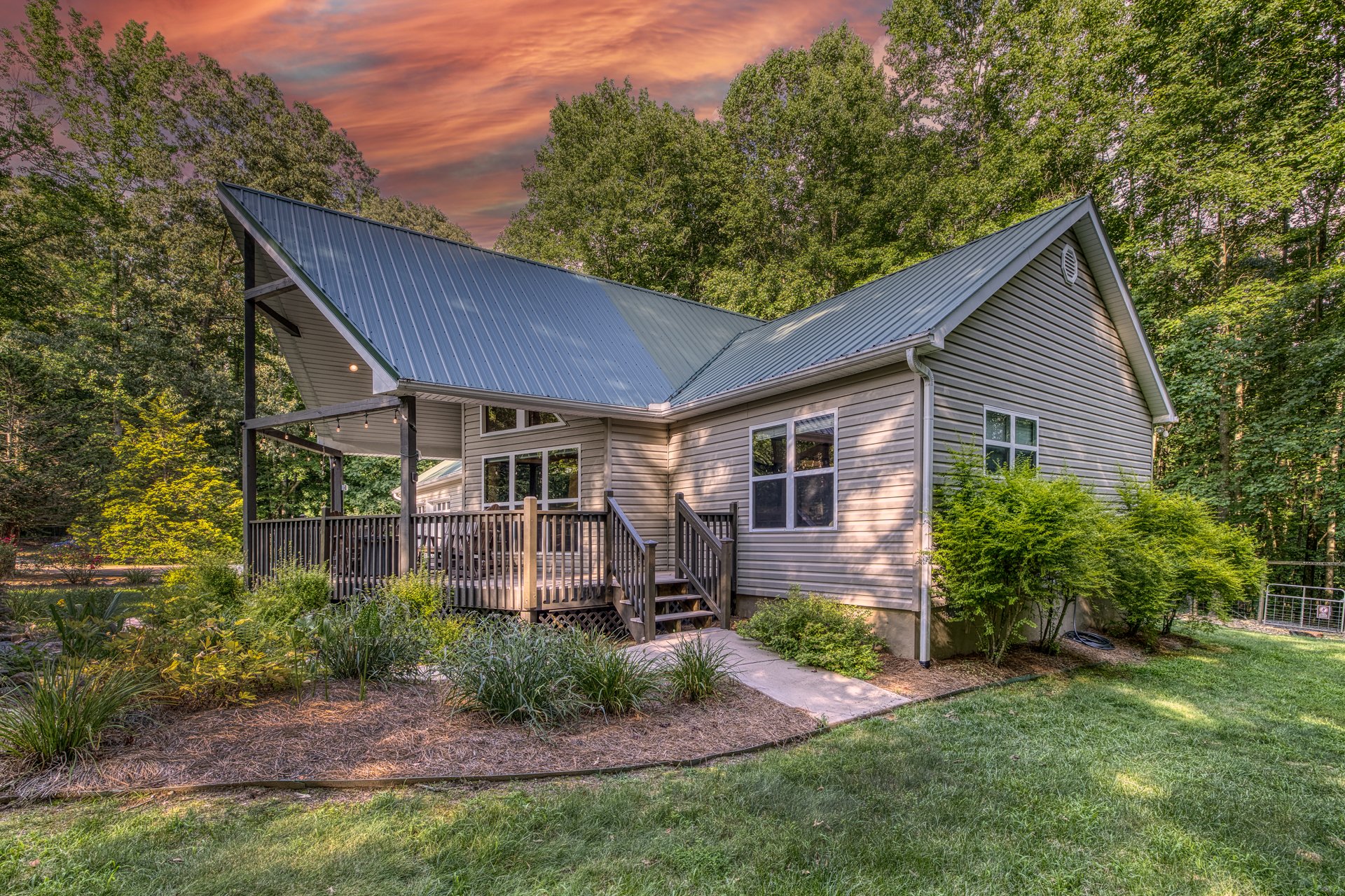 Charming front view of Sacred Waters, featuring a welcoming covered porch, rustic-modern design, and surrounded by lush trees for a peaceful retreat in nature.