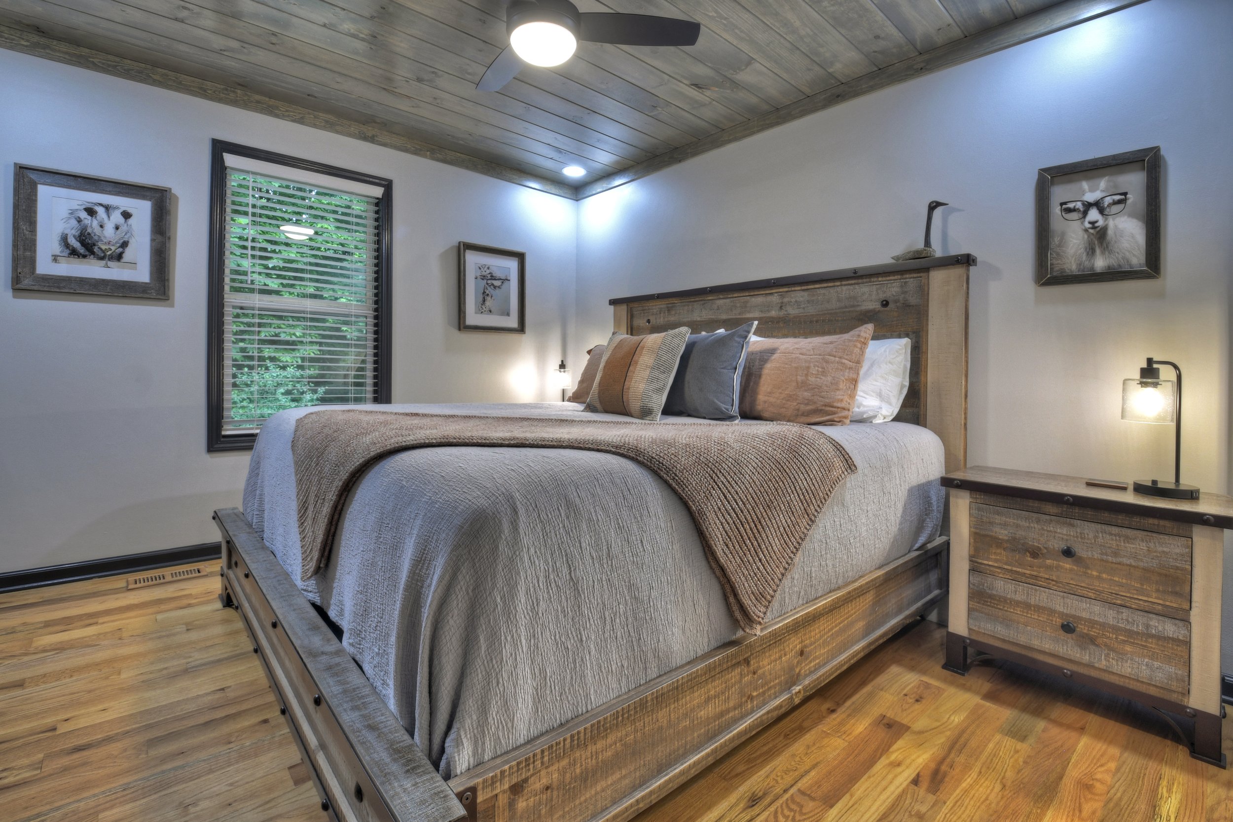 Cozy second bedroom featuring a king-size bed, soft linens, and warm rustic decor. A peaceful retreat with natural light and a serene forest view, perfect for a restful night's sleep.