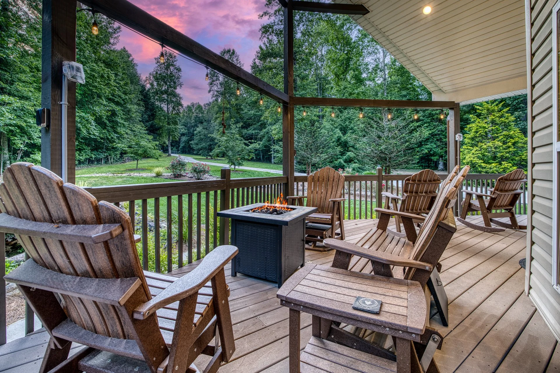 Covered front deck with a cozy seating area and a gas firepit, perfect for relaxing and enjoying the peaceful forest views in any season.