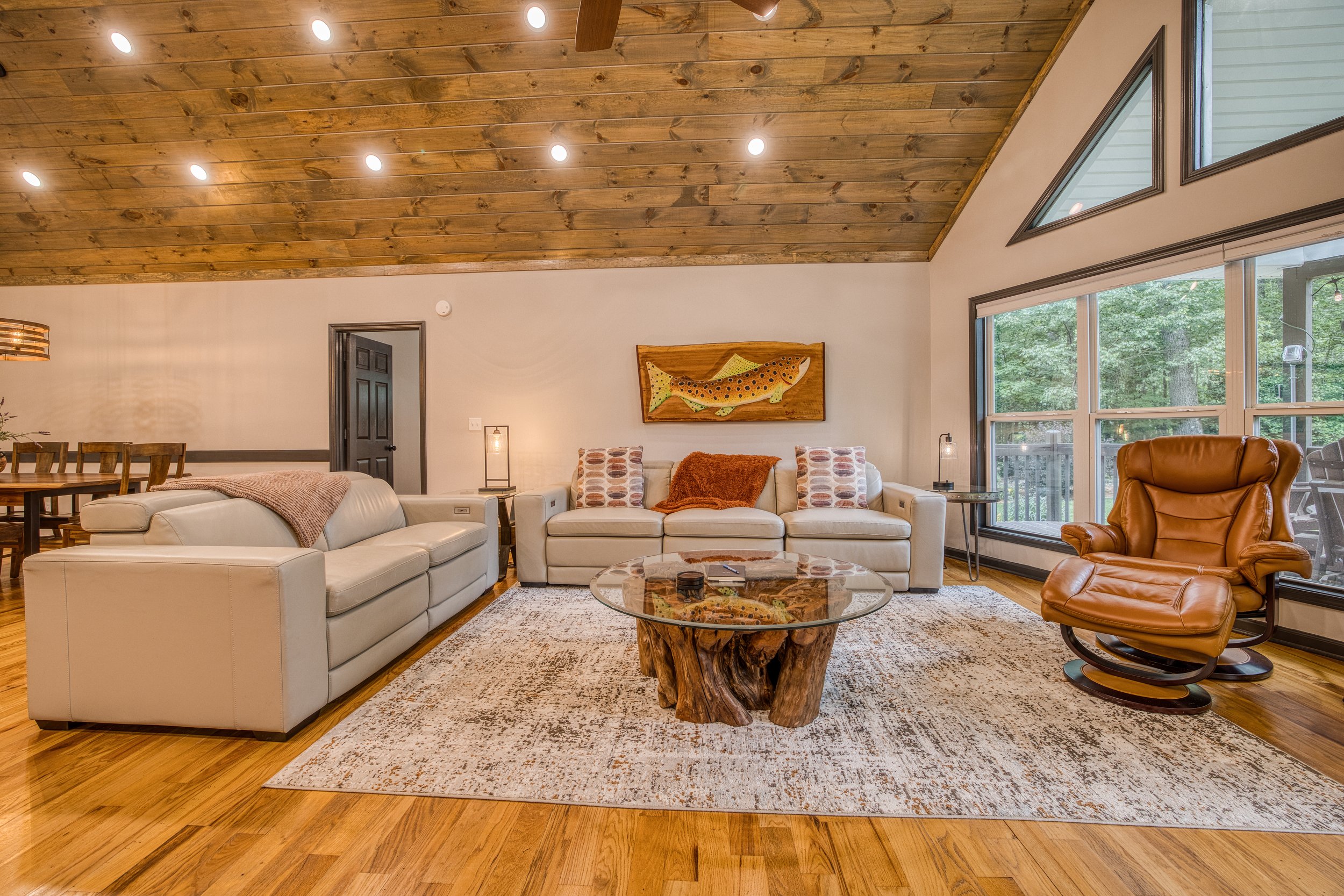 Living room with custom trout wall art, leather recliners, vaulted wood ceiling, and dog-friendly hardwood floors.