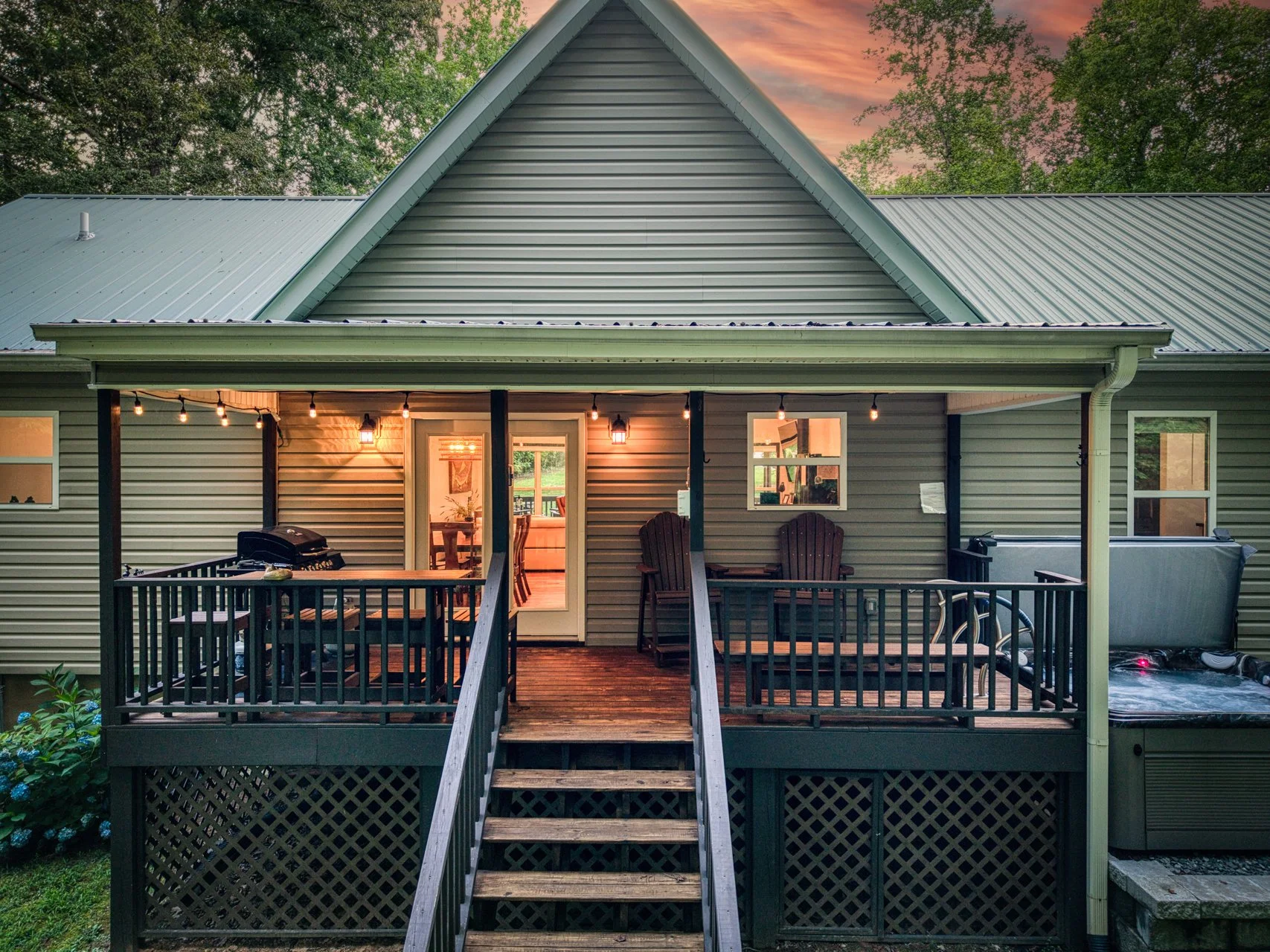 Covered back deck featuring a gas grill, outdoor dining space and seating, perfect for cooking and gathering while enjoying the serene treescape.