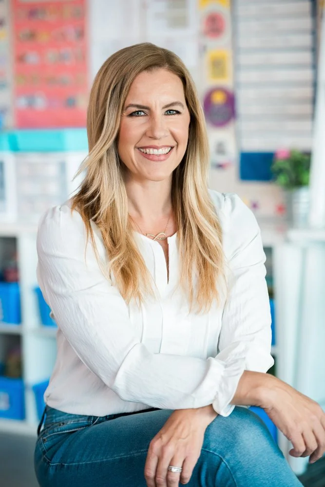 Karen Lara, teacher coach, sitting in an elementary classroom smiling.