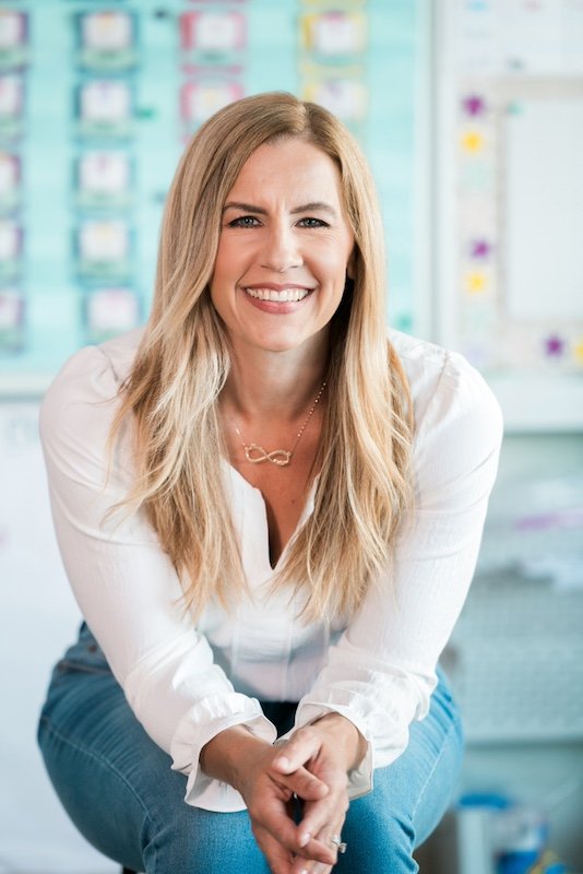 Karen Lara, educational consultant and teacher coach, sitting in an elementary classroom smiling at the camera.