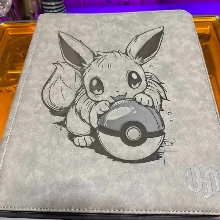 New drop on the laser: custom engraved binders that hit different. This one&rsquo;s got Eevee guarding the Pok&eacute; Ball like it&rsquo;s the last pack on the shelf, and the detail on this engraving came out insanely clean. We can engrave binders, 