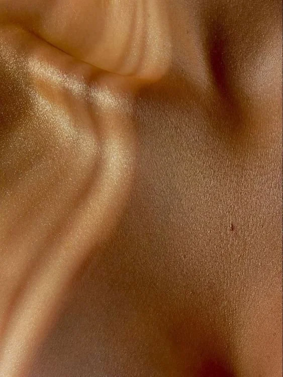 Close-up of a person's skin with a visible ear and cheek, showing smooth, shiny, and lightly textured skin.