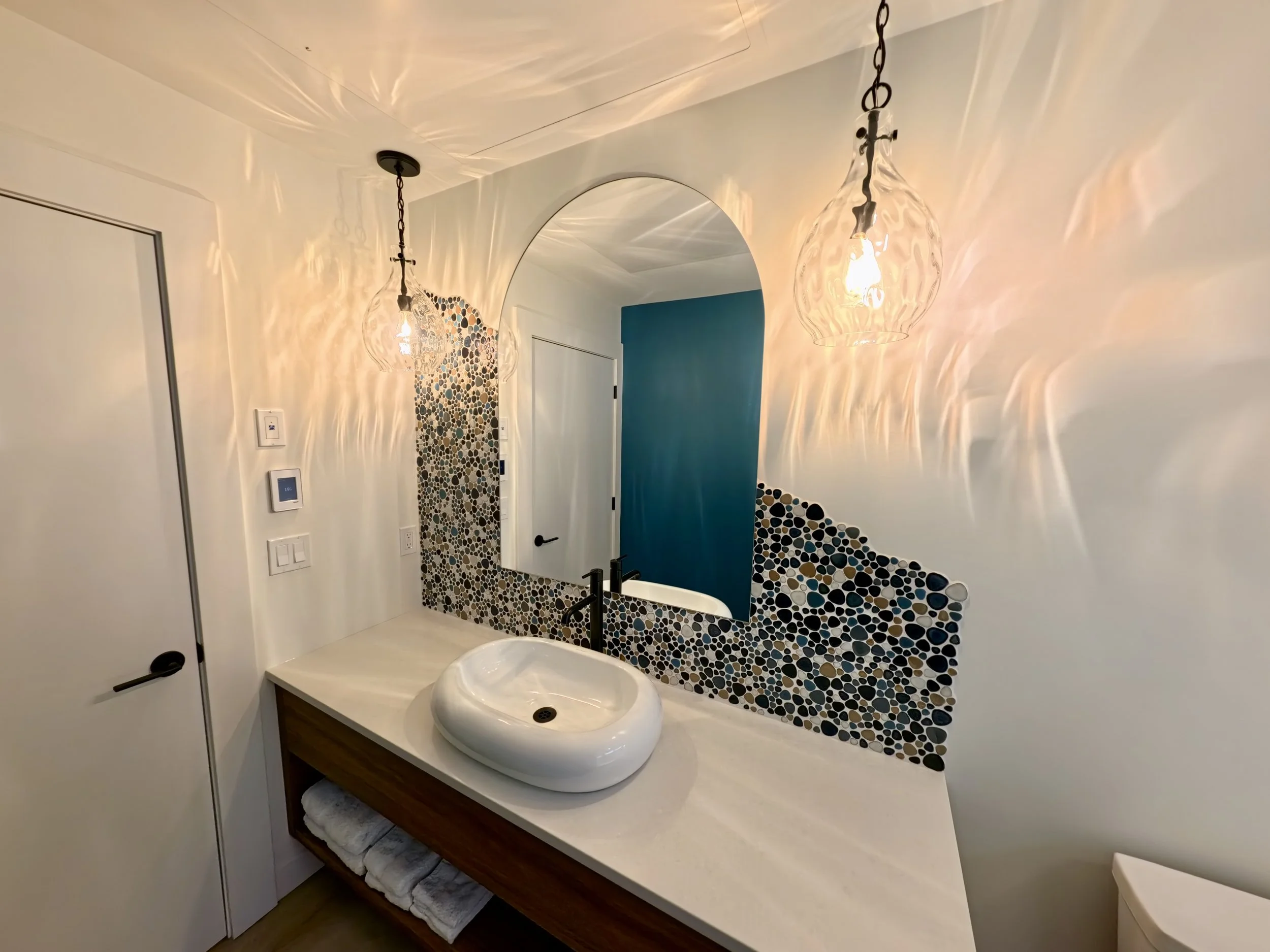 Custom cut mirror  in a bathroom with river tile back splash and blue walls
