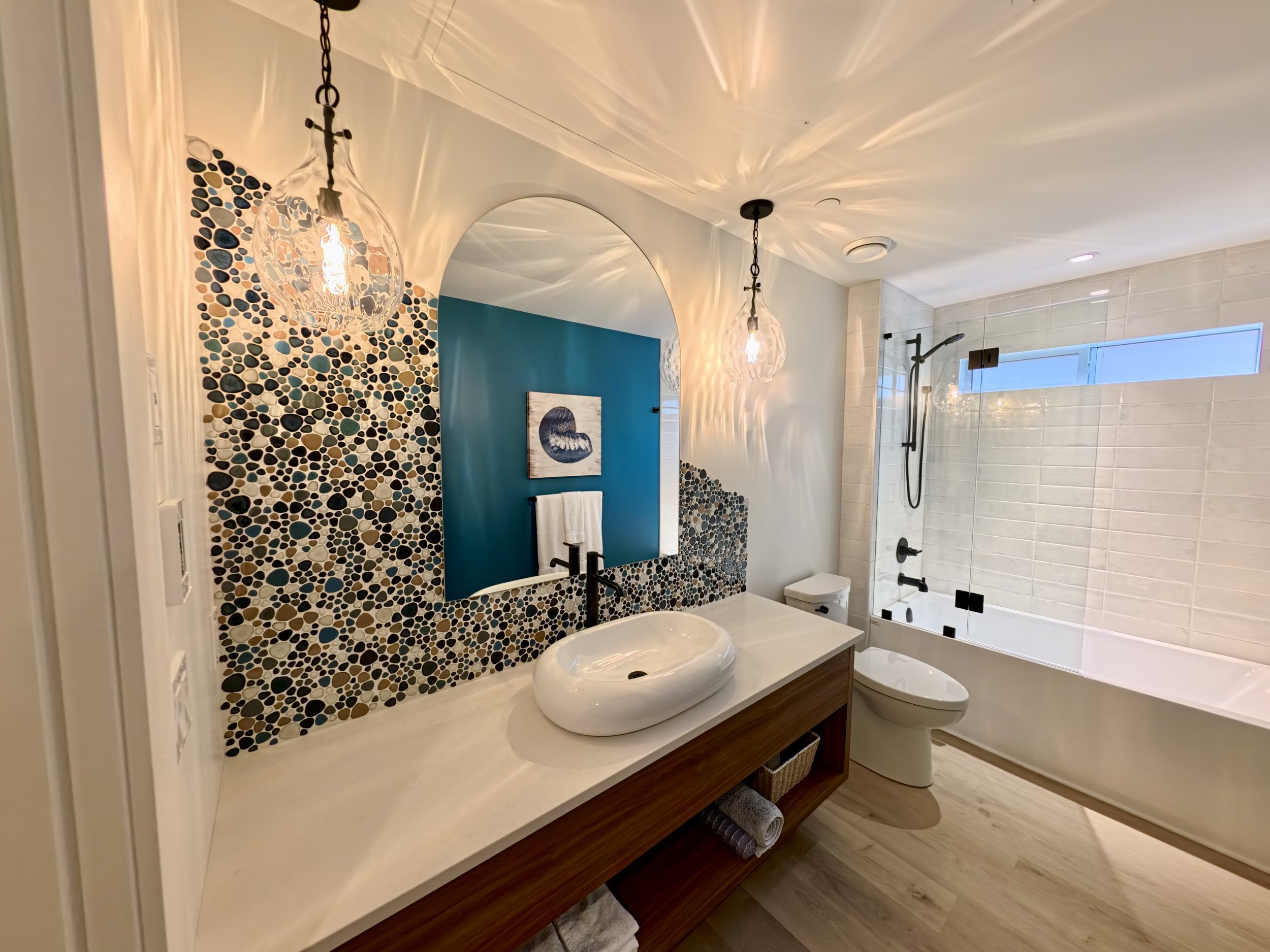 Custom cut mirror  in a bathroom with river tile back splash and blue walls