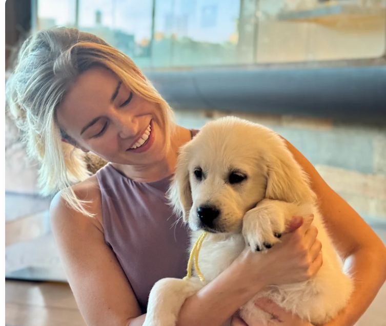 Woman holding a puppy at a Dog Yoga event sponsored by Puppy Yoga Club