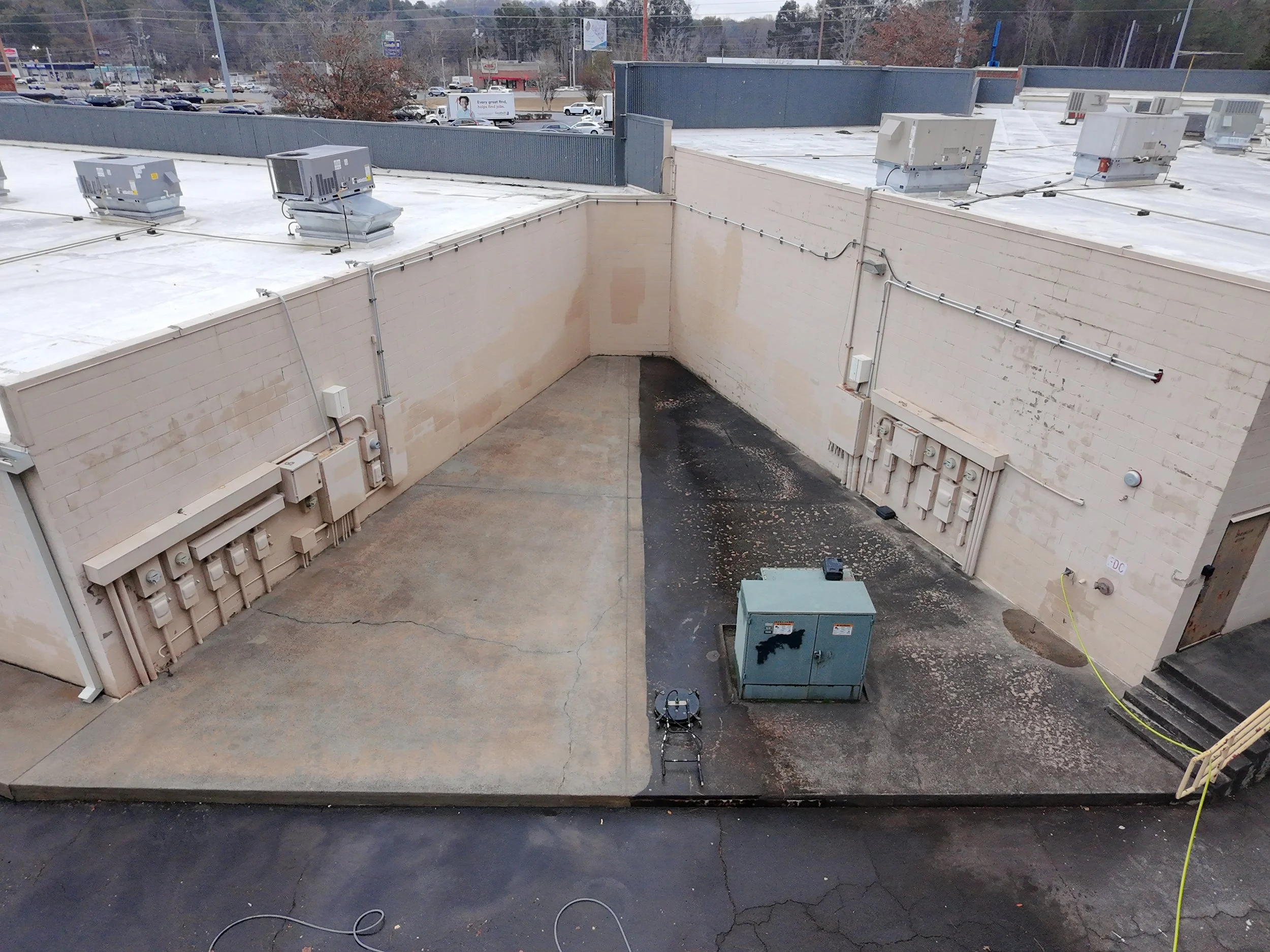Commercial pressure washing of concrete showing the left side being cleaned and the right side still being covered in grime and organic growth.
