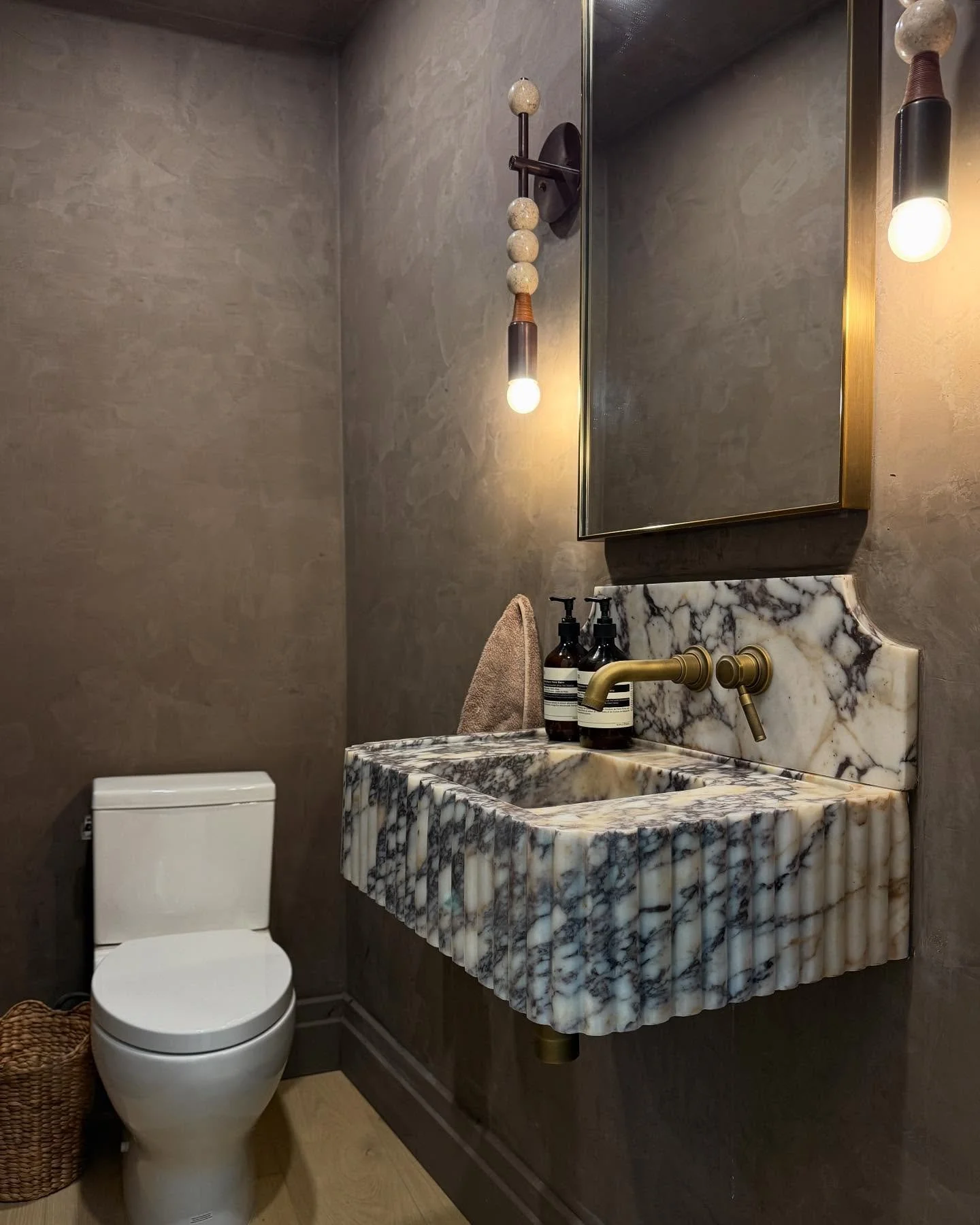 Would you believe this chic little powder room was once part of a guest bedroom closet?! We reimagined the layout, relocated the entry, and worked around subtly crooked walls to create a stunning hideaway. The fluted marble vanity, Roman clay walls, 