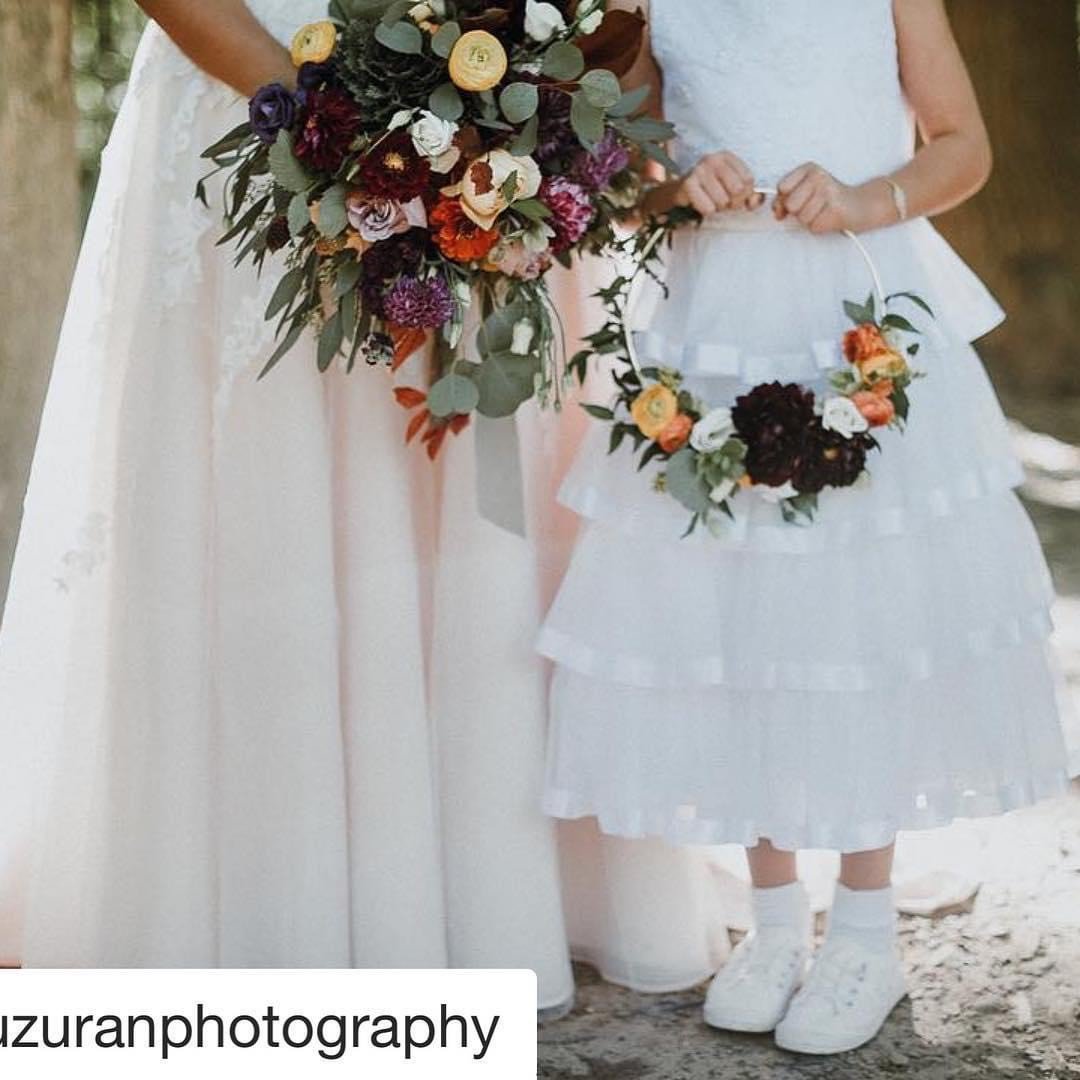 Bride and flower girl holding floral bouquets, wearing white dresses.