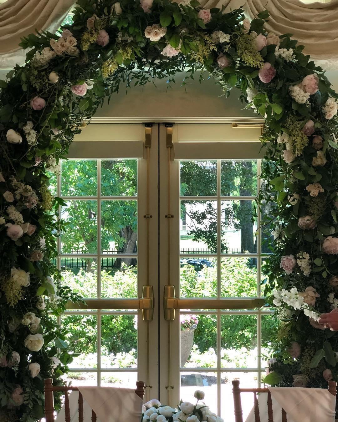 French doors adorned with floral garland, view of garden outside