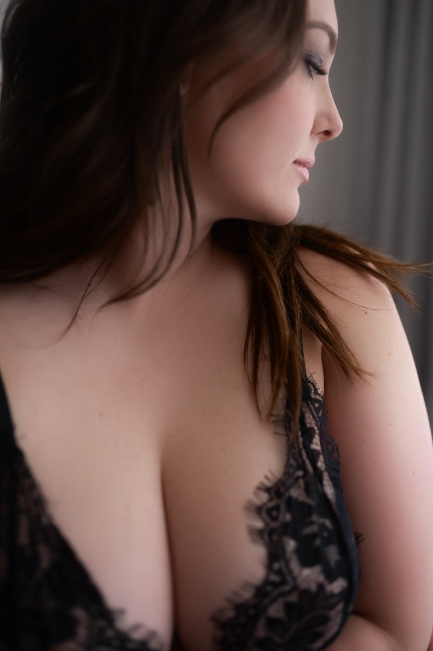 Close-up of a woman in lingerie, profile view, in soft lighting.