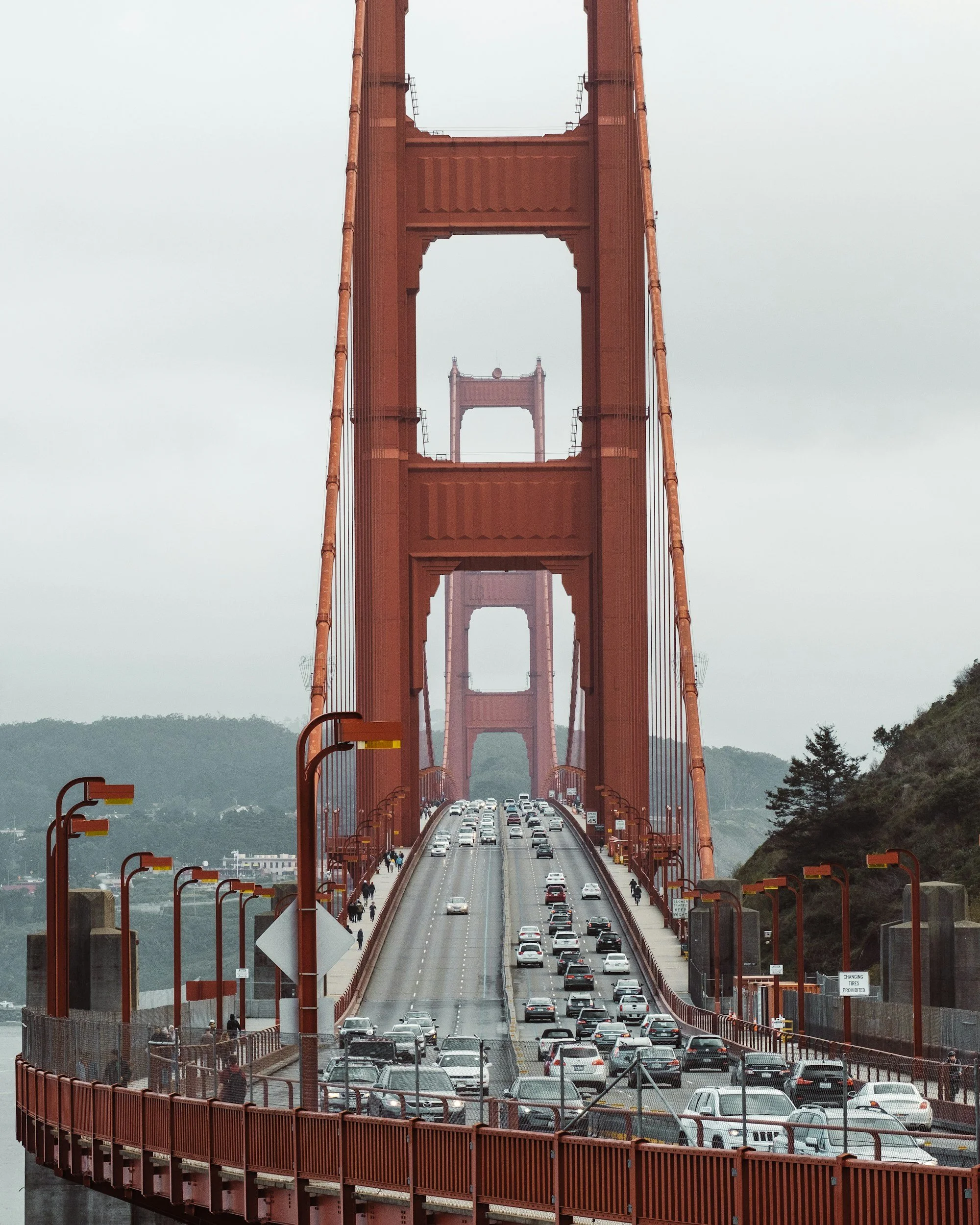 Golden Gate Bridge in San Francisco with traffic and pedestrians, overcast sky.