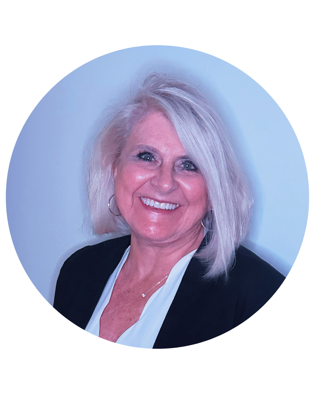 Smiling woman with short blonde hair wearing a black jacket and white blouse.