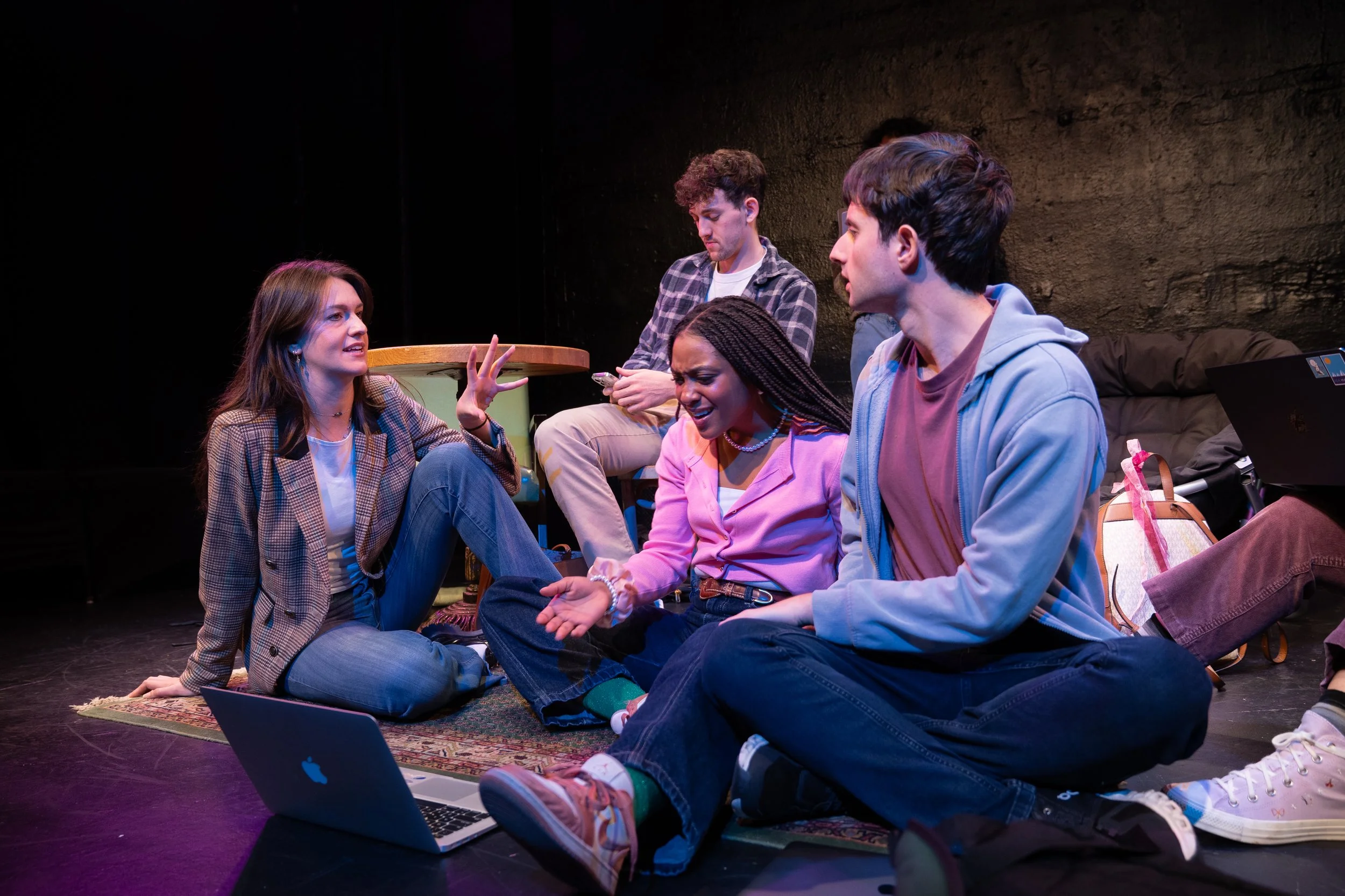 Remidy Destyn Dixon in "In Chief" - Group of young adults sitting on a rug and engaging in an intense conversation or debate in a dimly lit room, with a laptop open in front of them.