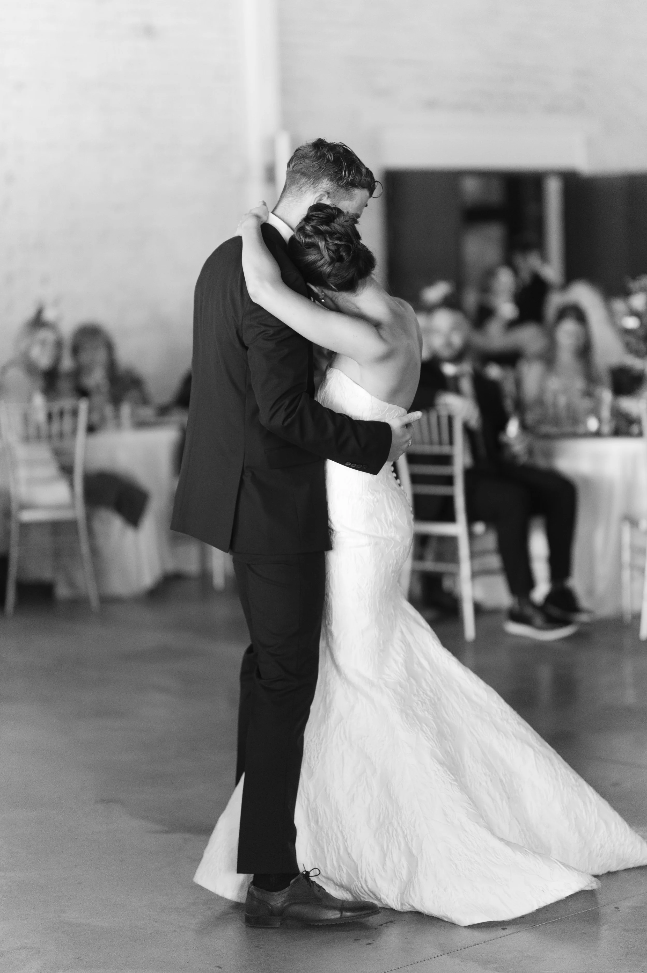 Black and white photo of a bride and groom dancing at their wedding reception.