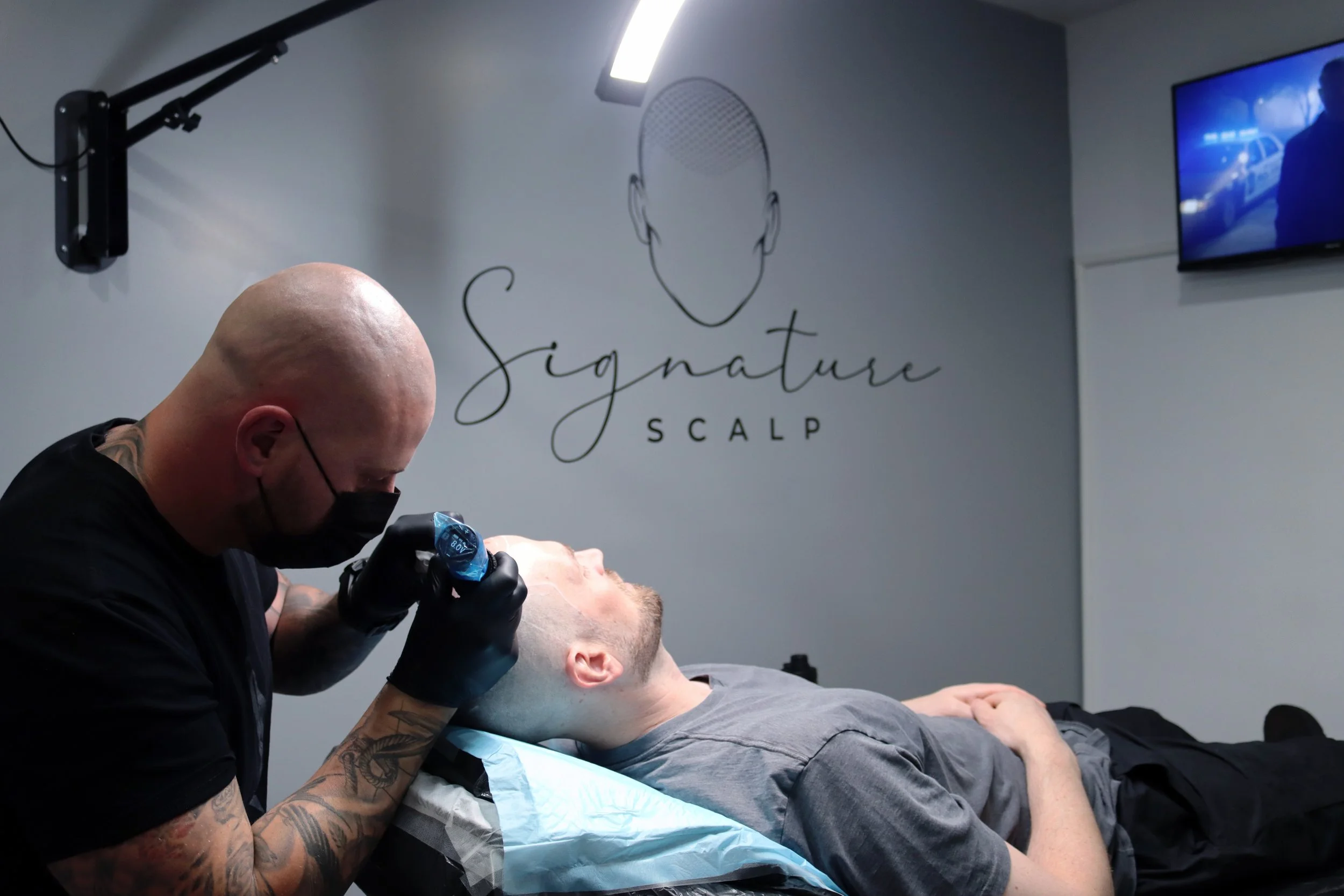 Signature Scalp Adelaide SMP artist performing scalp micropigmentation treatment on a male client at the Marden studio