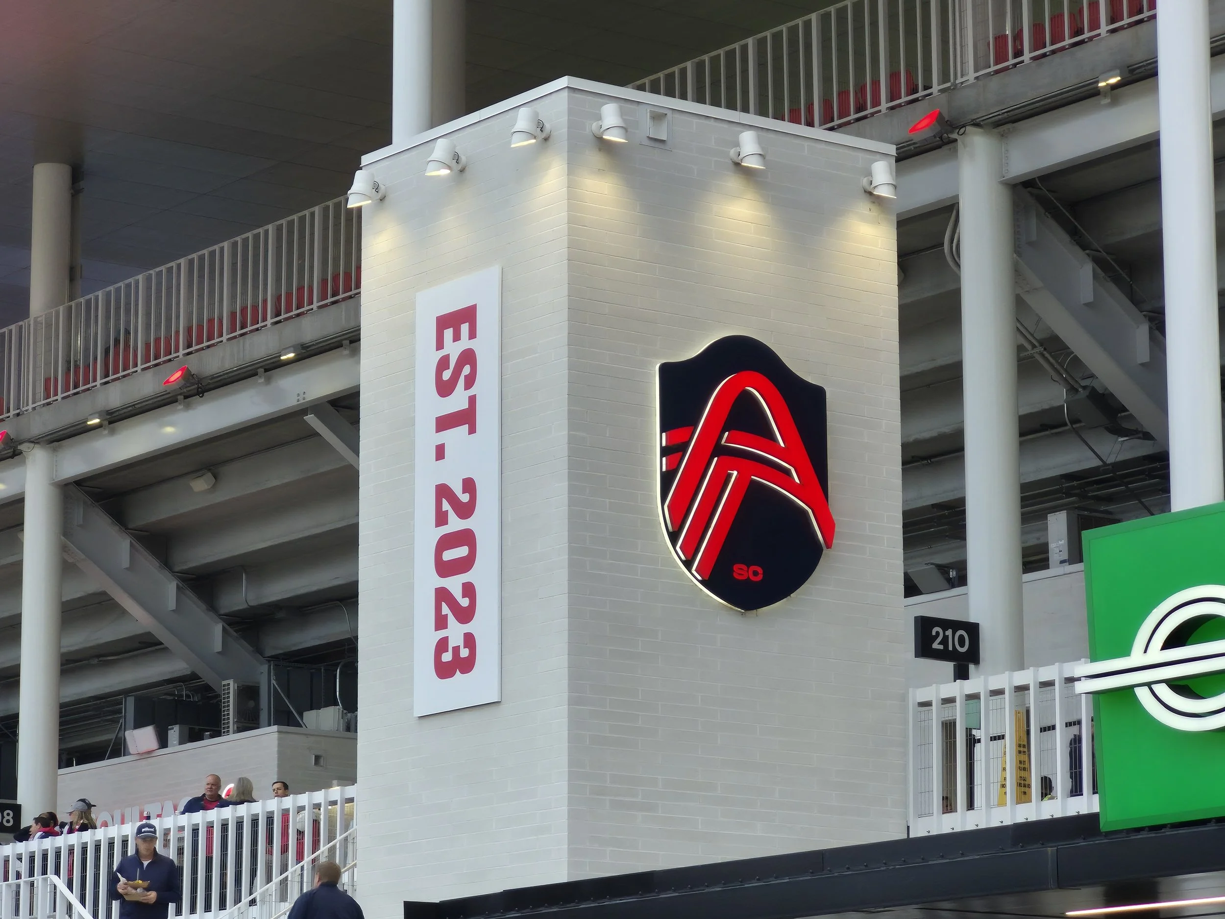 Stadium structure with "EST. 2023" sign and logo at section 210 entrance.