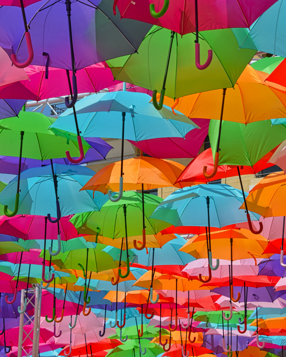Colorful umbrellas suspended overhead in vibrant colors including pink, green, orange, purple, blue, and red.