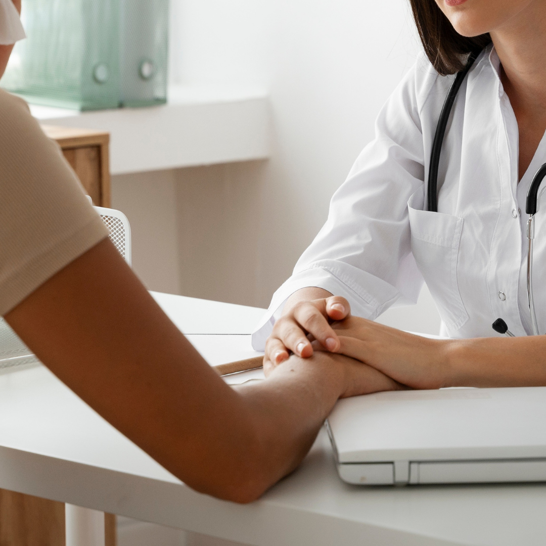 Doctor holding a patient's hand during a consultation in a clinic.