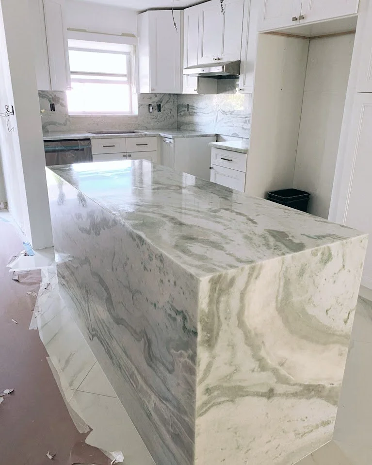 Kitchen with white cabinets, marble countertops, and a marble kitchen island.