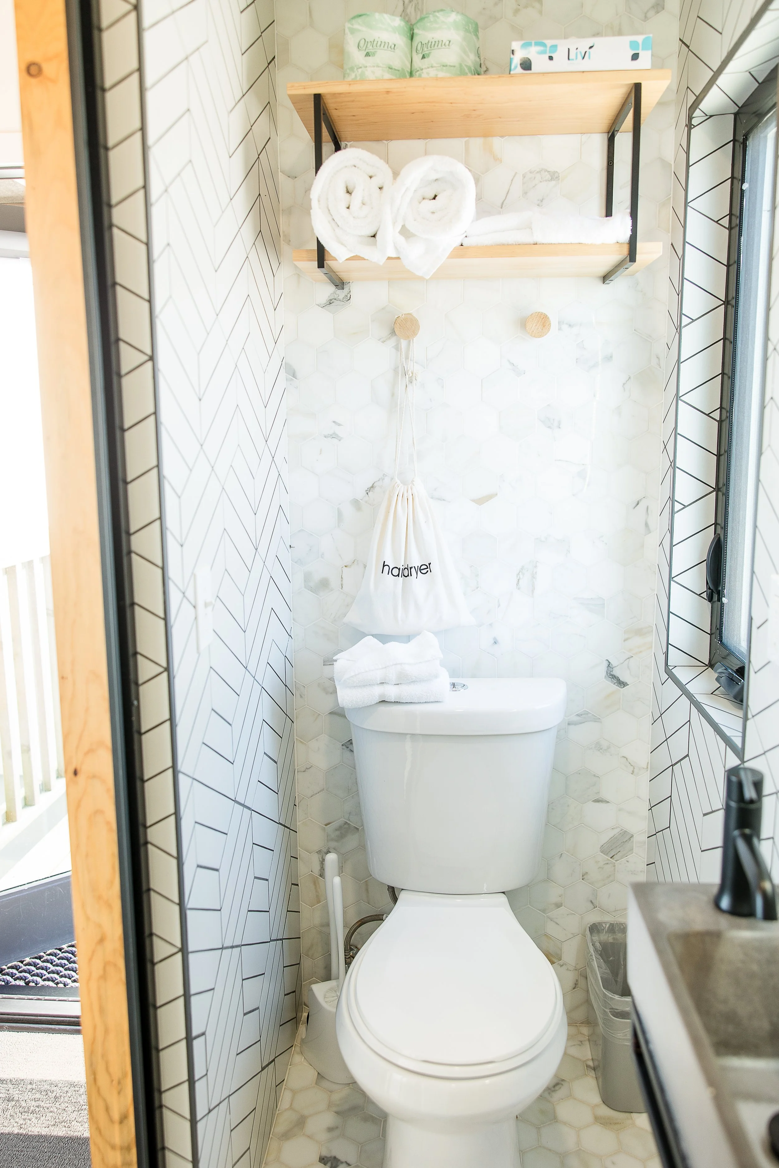 Upscale bathroom in an Osprey cabin featuring a circular black-framed mirror, industrial wall sconce, and a wood vanity with a white vessel sink.