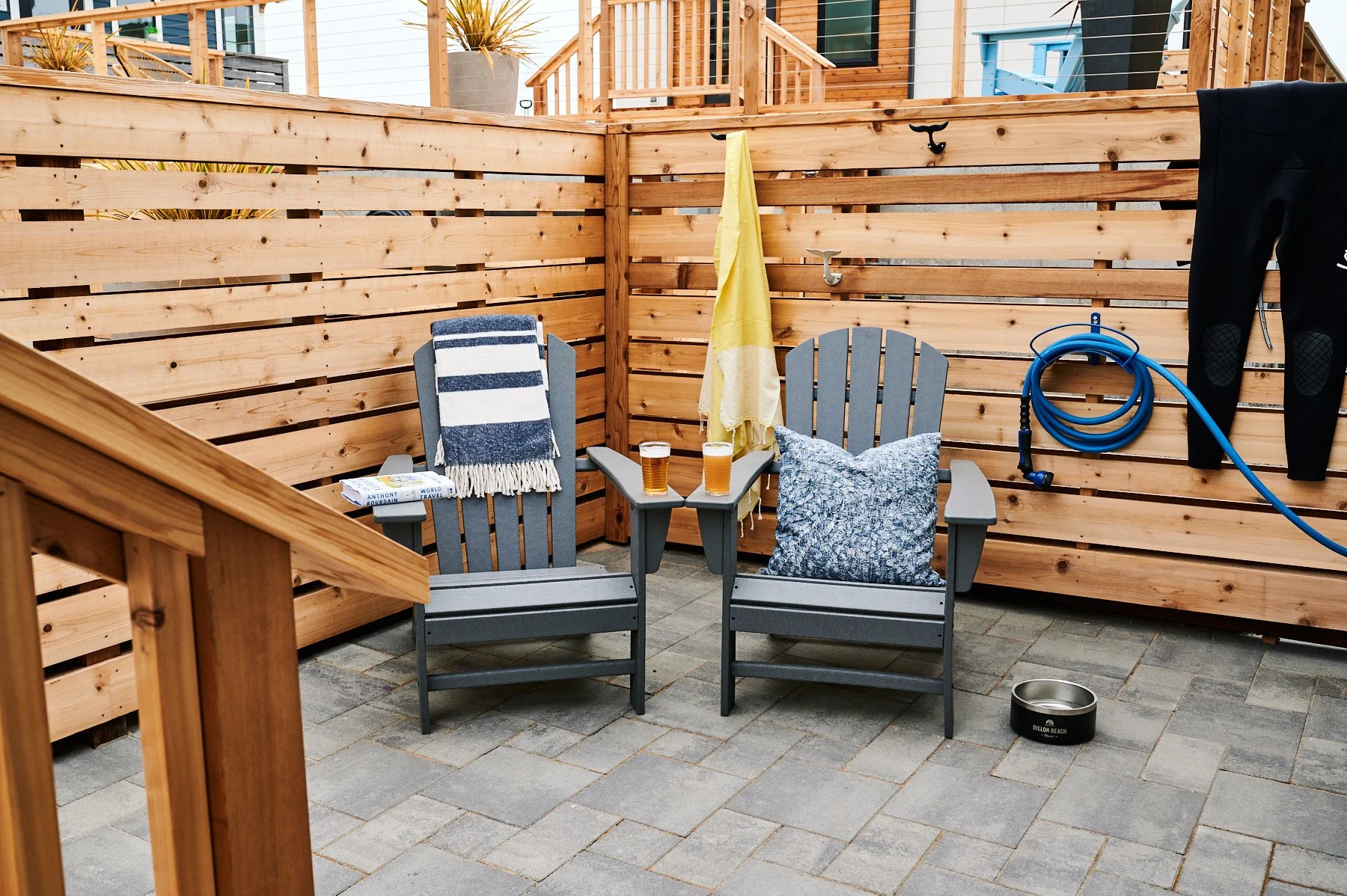 Private patio at Dillon Beach Resort with Adirondack chairs, beers, and dog bowl behind a wood privacy fence.
