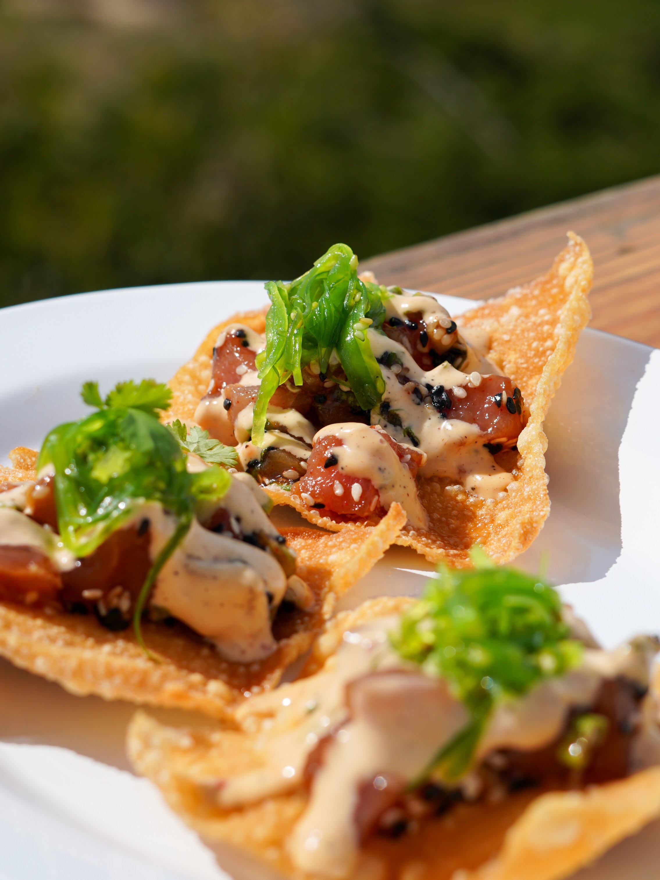 Three Poke Tostadas with tuna, sesame seeds, green onion, wakame, spicy aioli on crispy wonton chips.