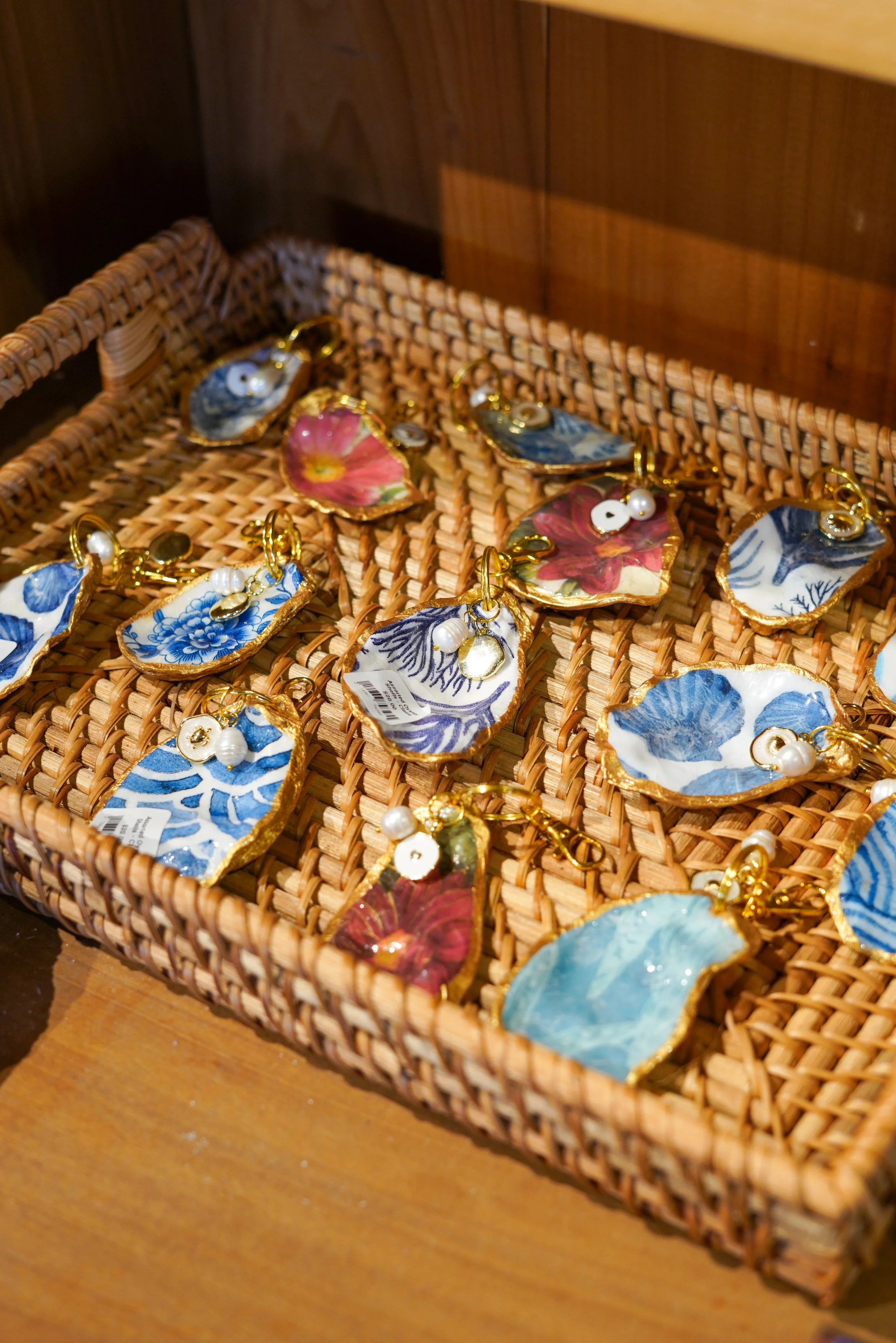 Decorative shell-shaped earrings in a woven basket on a wooden surface.