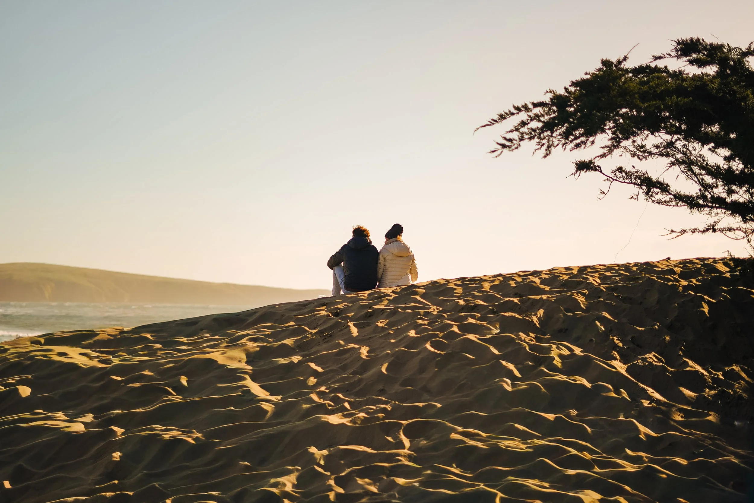 couple-sitting-sand-dune-dillon-beach-coastline-tamales-bay.jpg