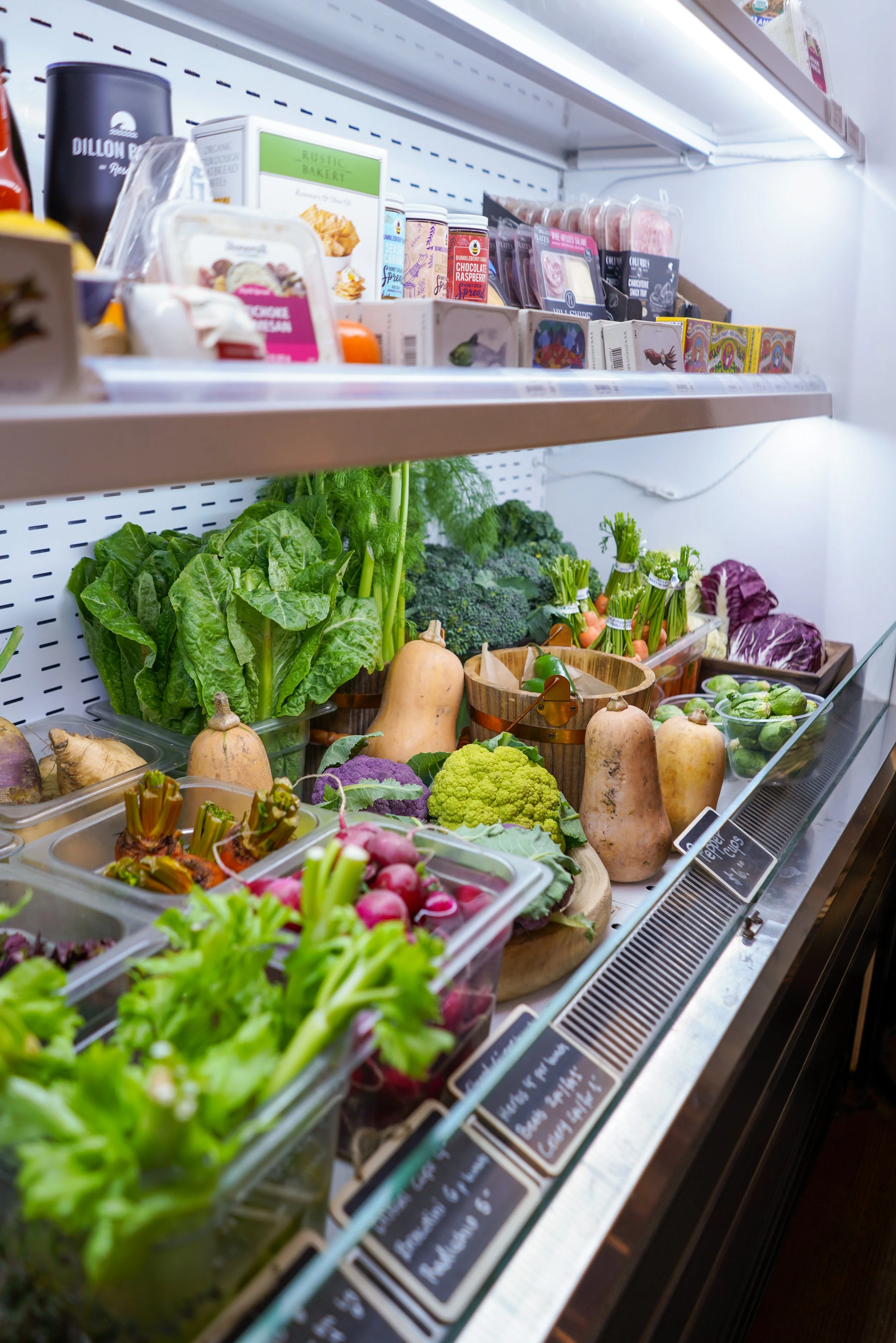 Fresh vegetables including lettuce, radishes, broccoli, carrots, and butternut squash displayed at a grocery store.