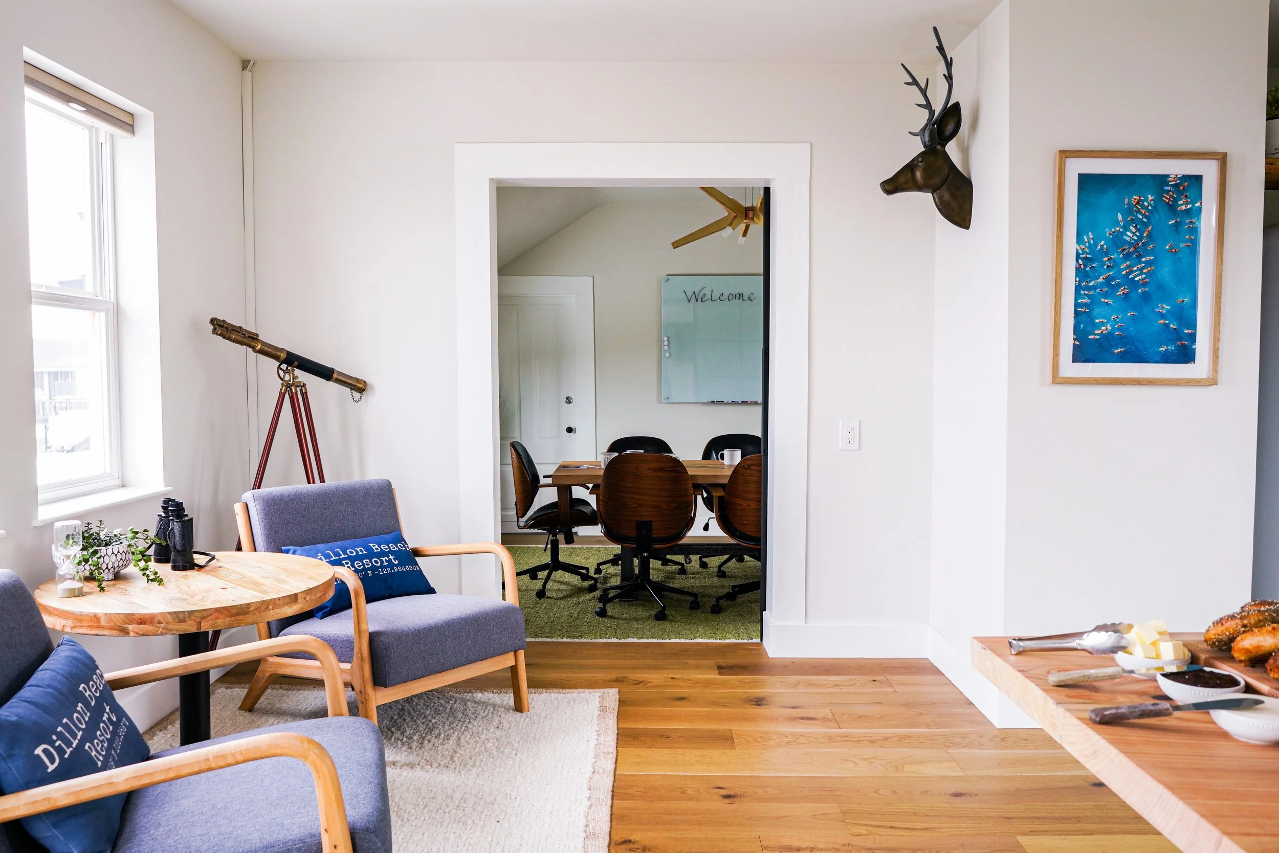 A multi-room corporate suite at Dillon Beach Resort, featuring a coastal-style lounge area with a telescope and an adjacent private conference room.