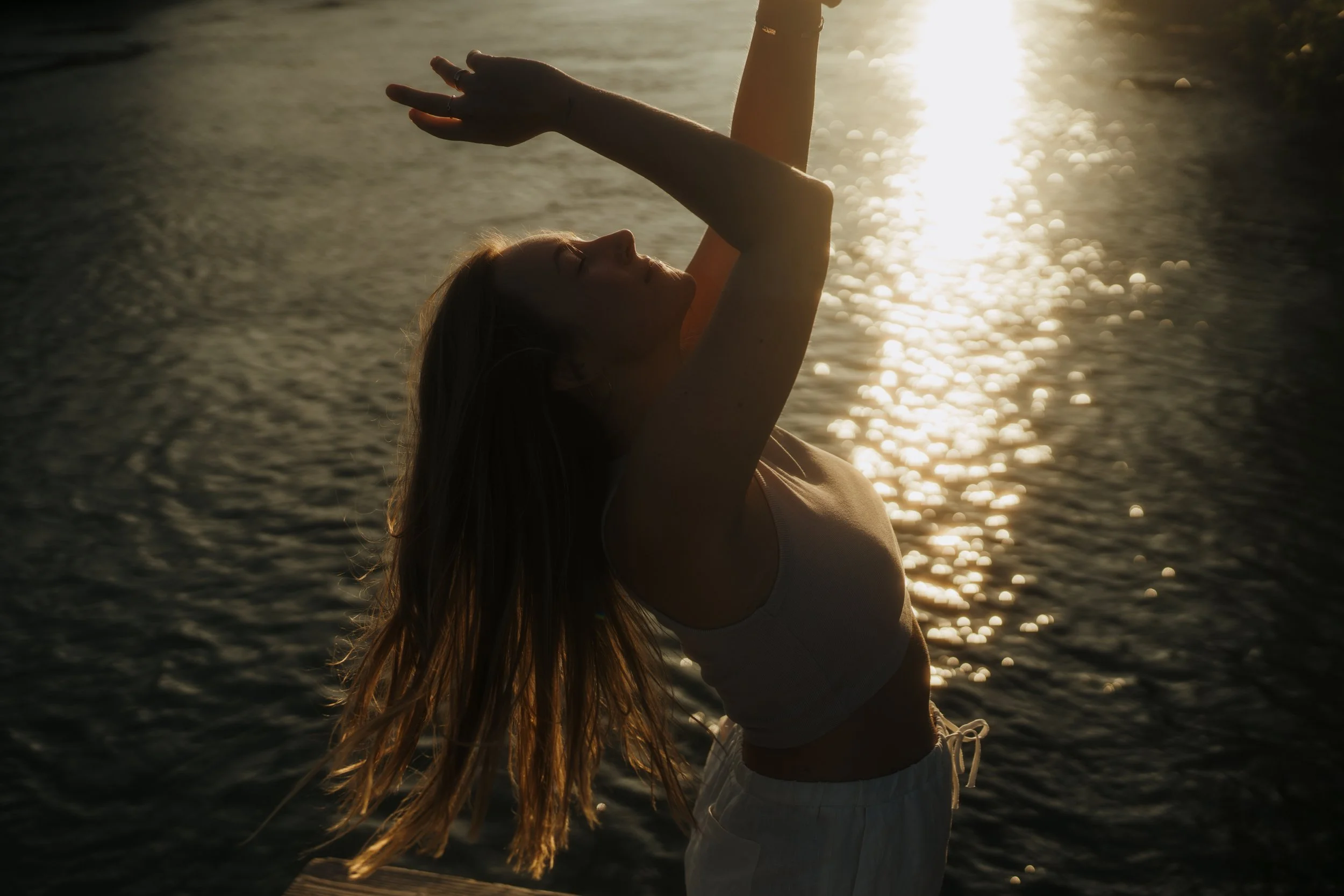 Eine junge Frau macht Yoga am Strand bei Sonnenuntergang.