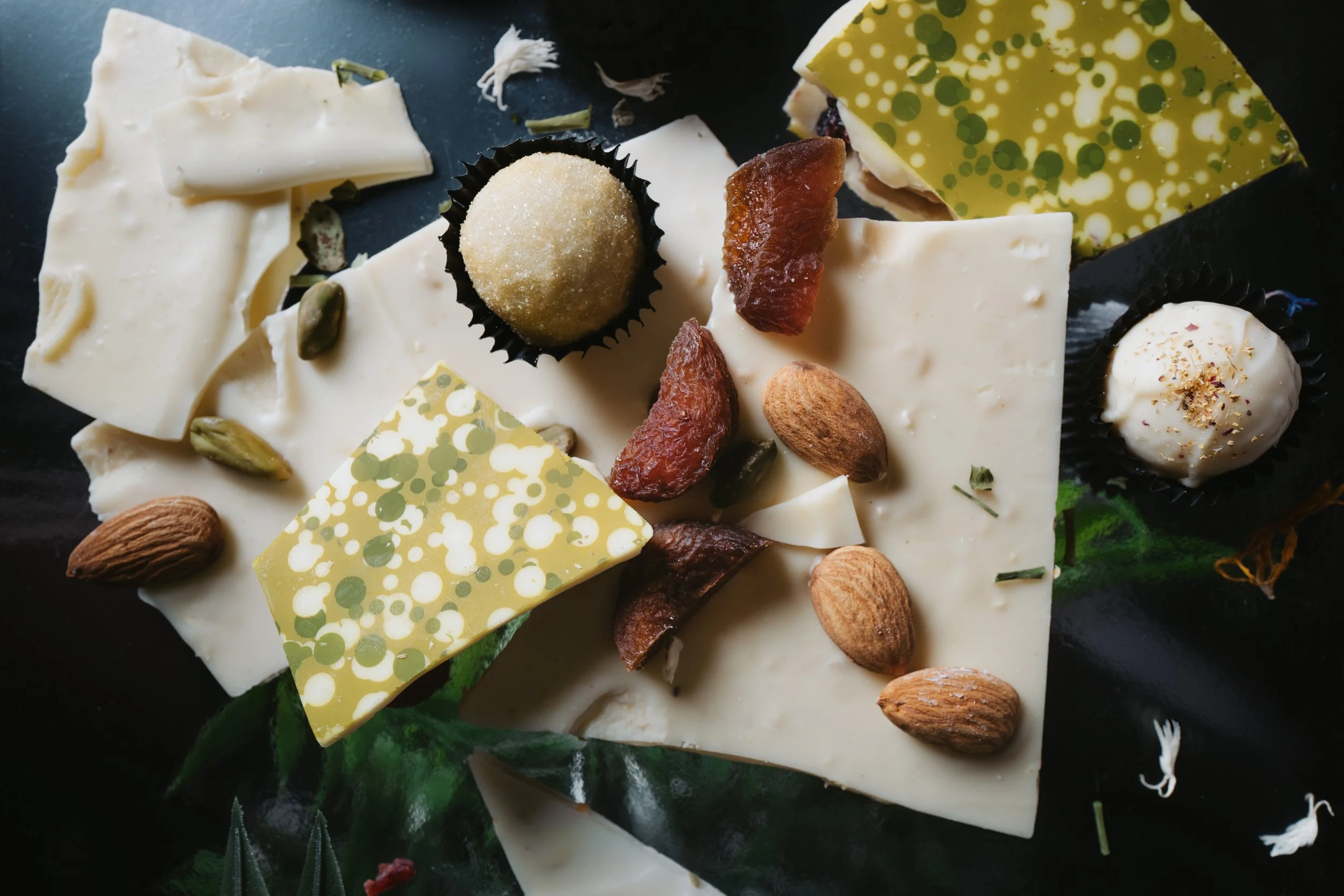 Verschiedene Sorten Käse mit Nüssen und Trockenfrüchten auf einem schwarzen Hintergrund.