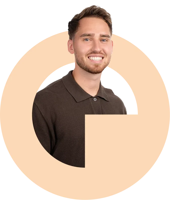 Ein Mann mit braunen Haaren und Bart trägt ein schwarzes Polo-Shirt, lächelt und sieht in die Kamera, vor einem grafischen Hintergrund mit geometrischen Formen.