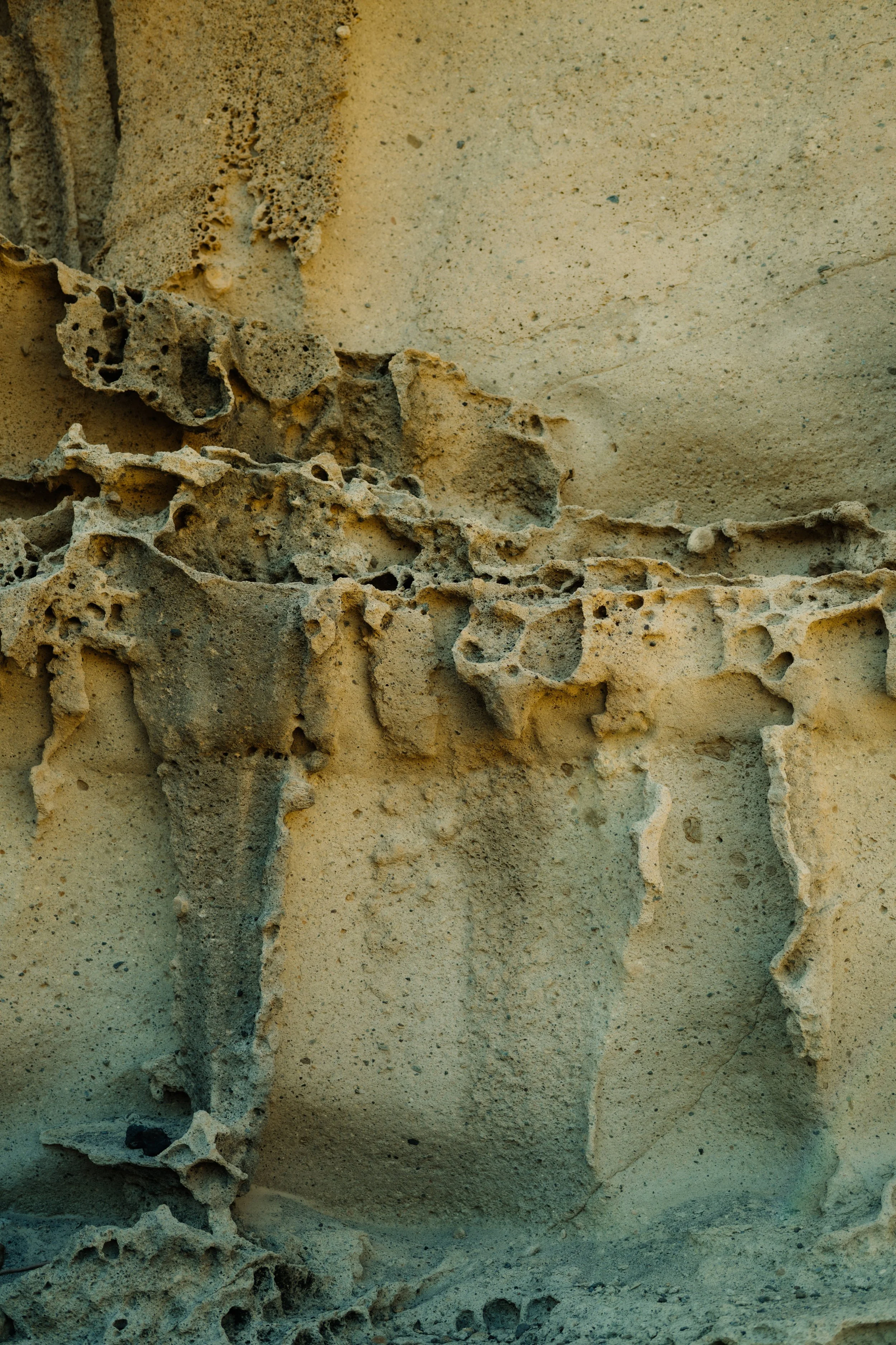 Nahaufnahme einer alten, zerbrochenen Wand aus feurigem Sandstein mit Rissen und abbröckelndem Material.