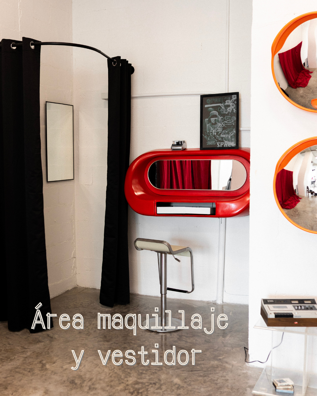 Área de maquillaje y vestidor con espejo redondo y cortinas negras.