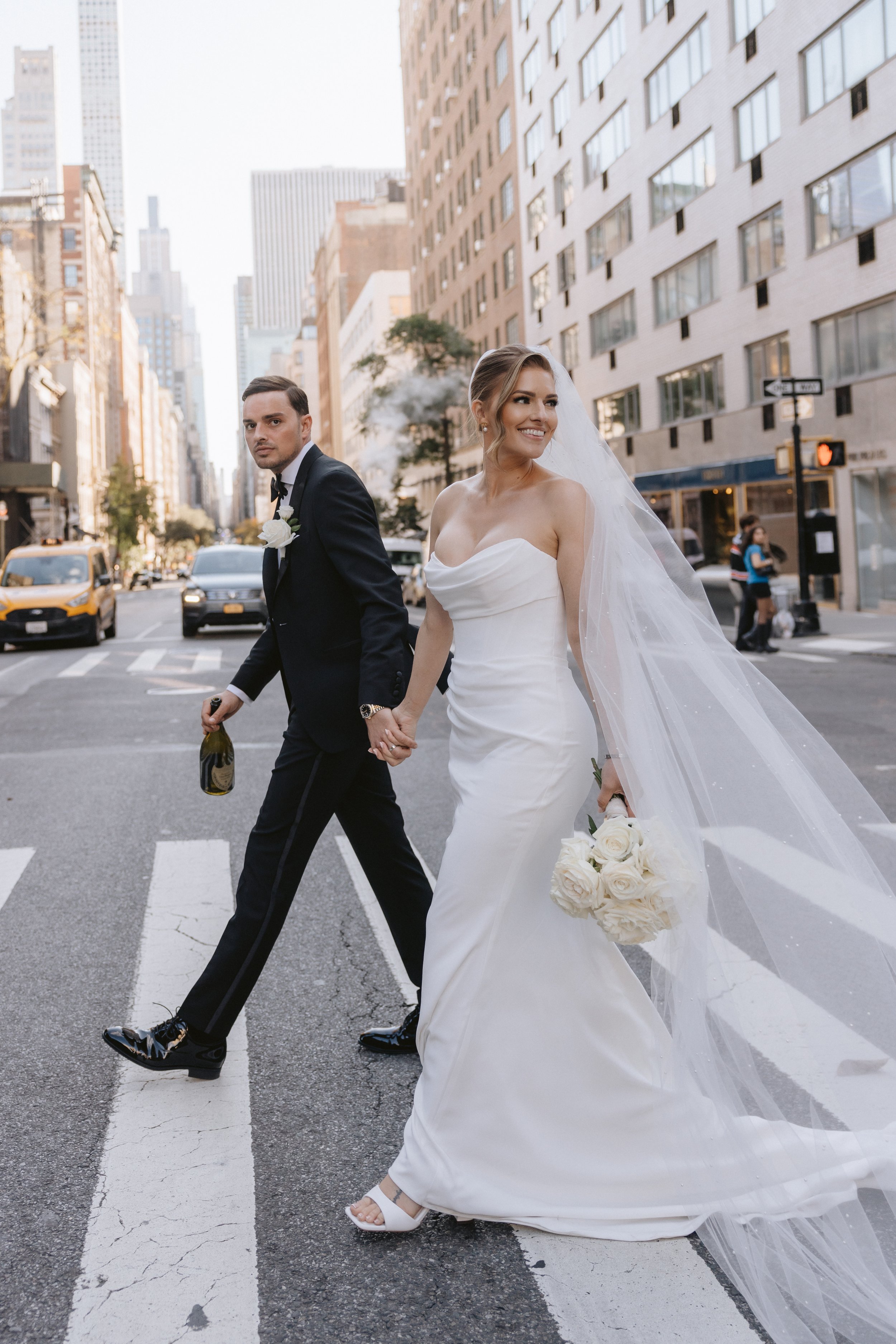 Beautiful street style photo of a couple on their wedding day in New York, bride carries classic but modern bouquet of white roses