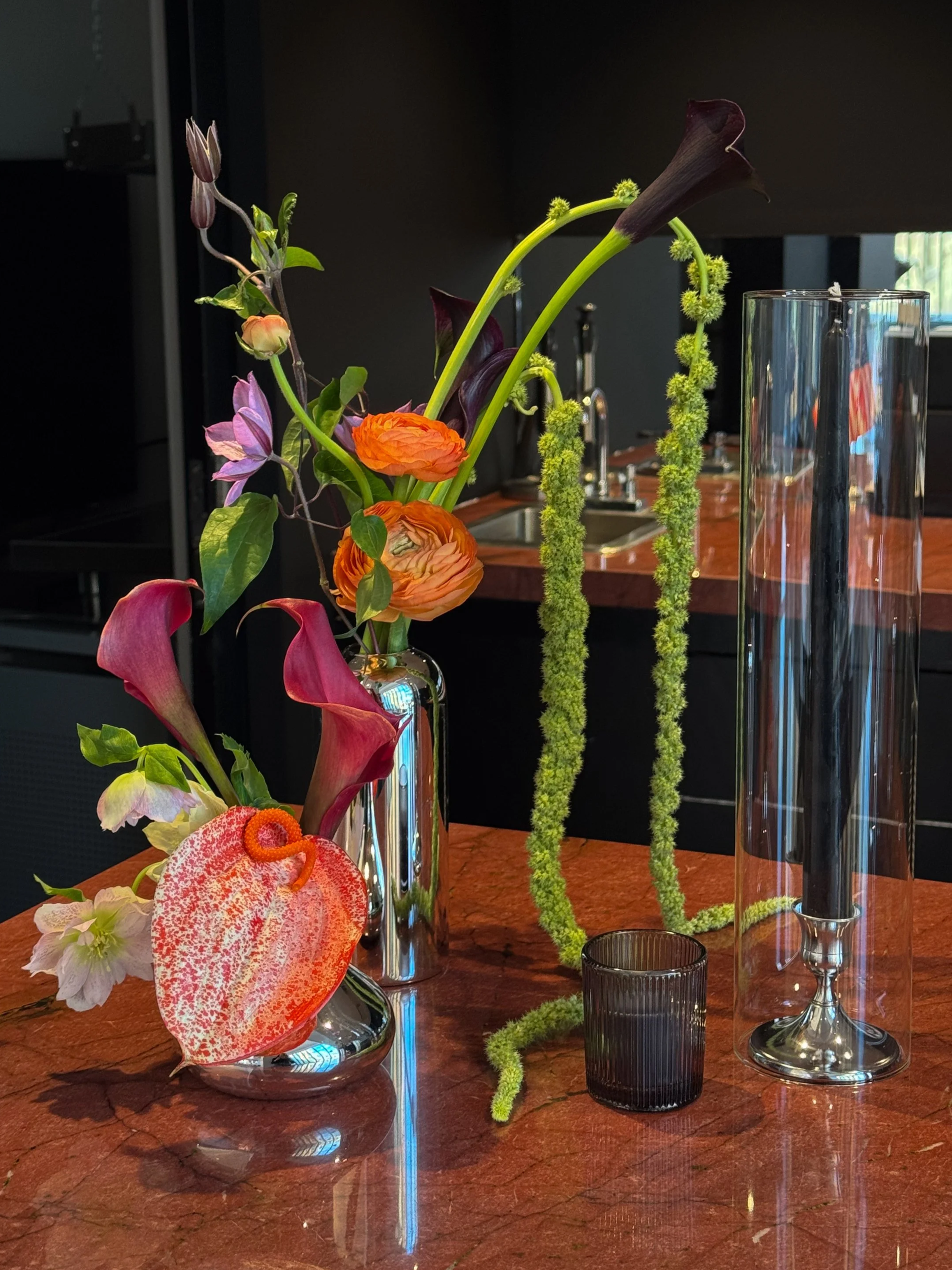 Whimsical colorful florals in chrome bud vases: green amaranth, anthurium, ranunculus and clematis