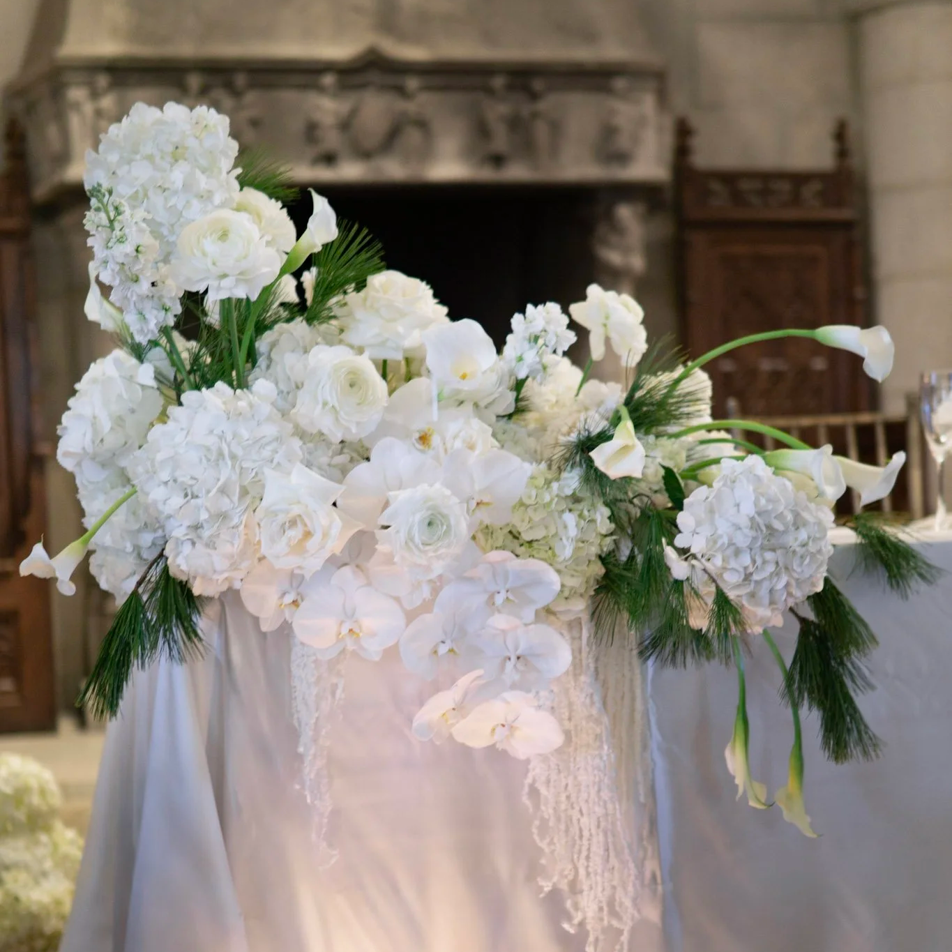White floral arrangement with roses, orchids, hydrangeas and ranunculus for the sweetheart table