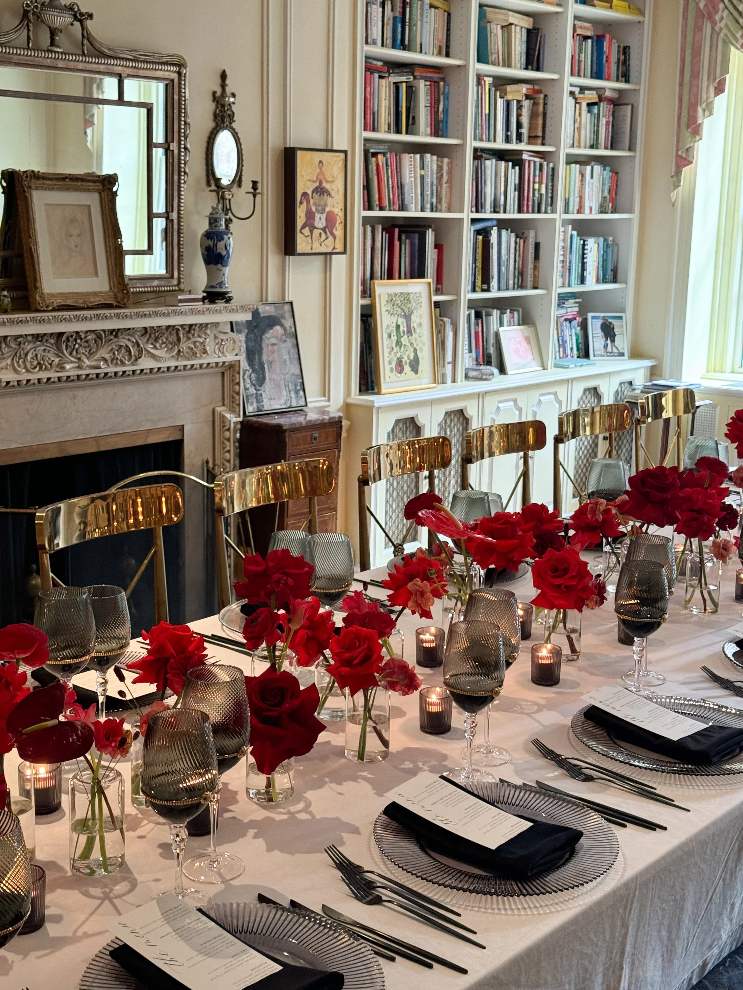Stunning tablescape in red and black color palette. Red roses, tulips, anthurium and ranunculus in bud vases