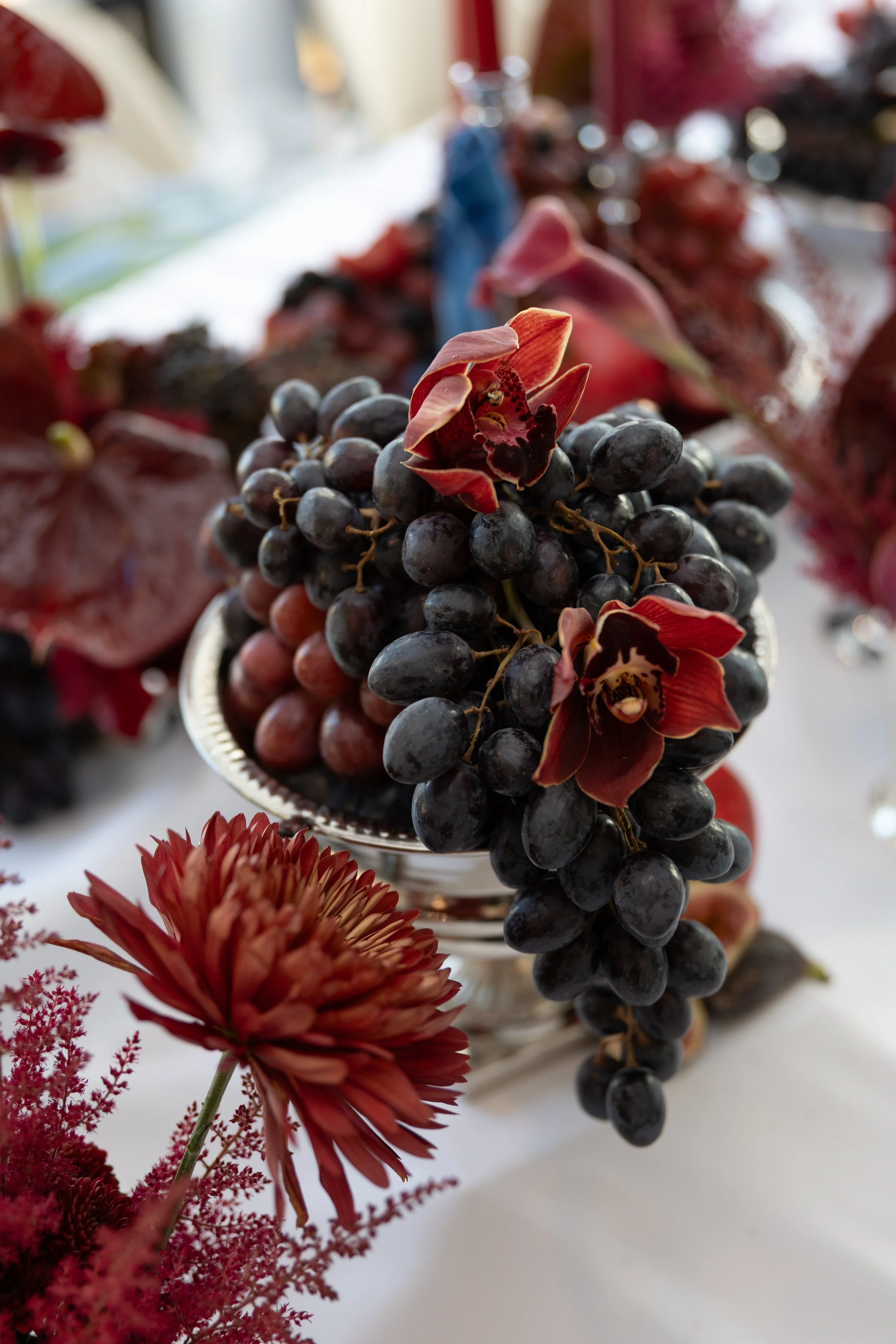 Stunning sculptural burgundy tablescape decorated with grapes and orchids