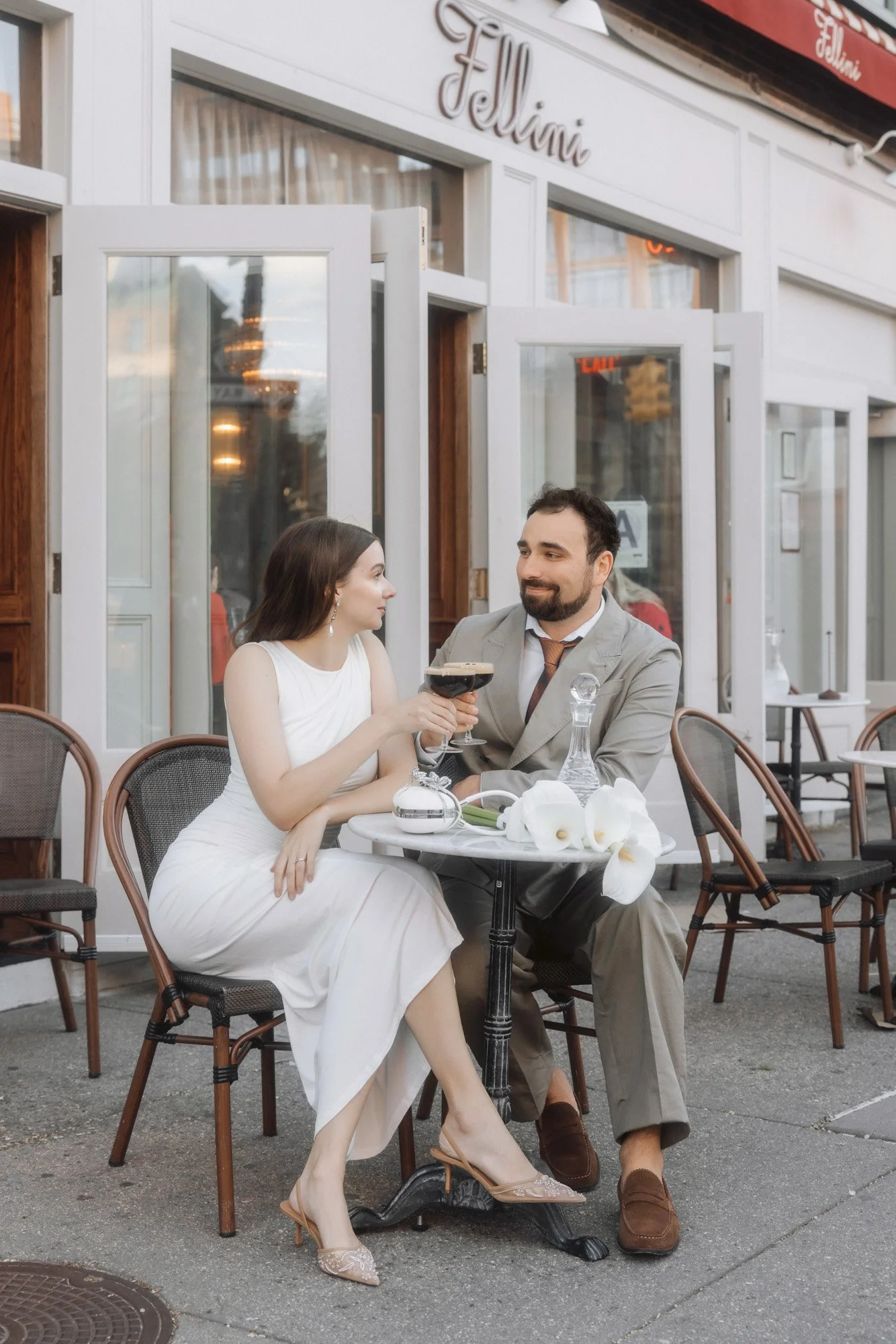 New York City elopement. Bride and a groom sitting in a cafe with a bouquet of white calla lilies