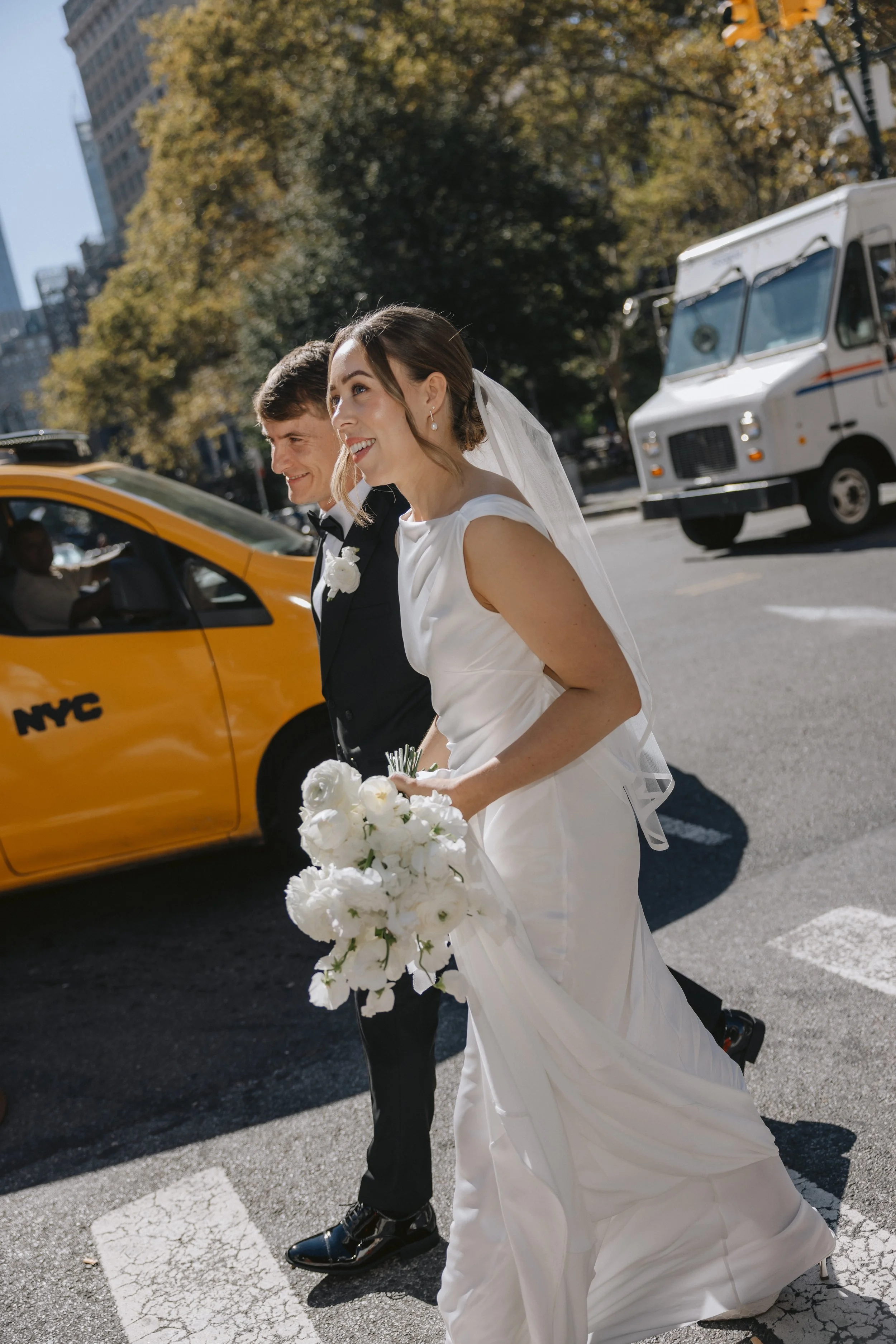 A bride and groom walking on a New York City street with an airy stunning bridal bouquet