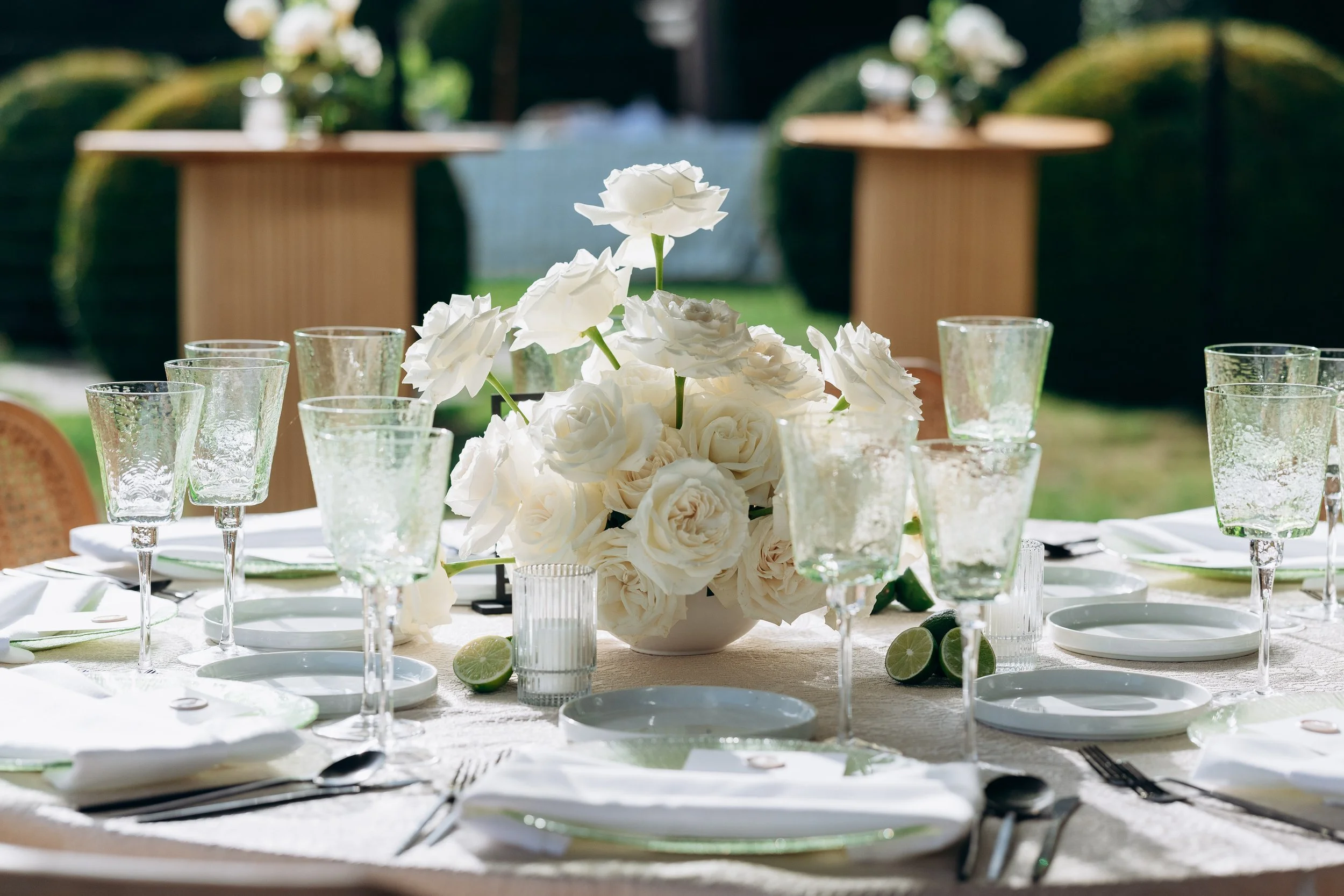 Outdoor table setting with a large elegant centerpiece of white roses in Hamptons