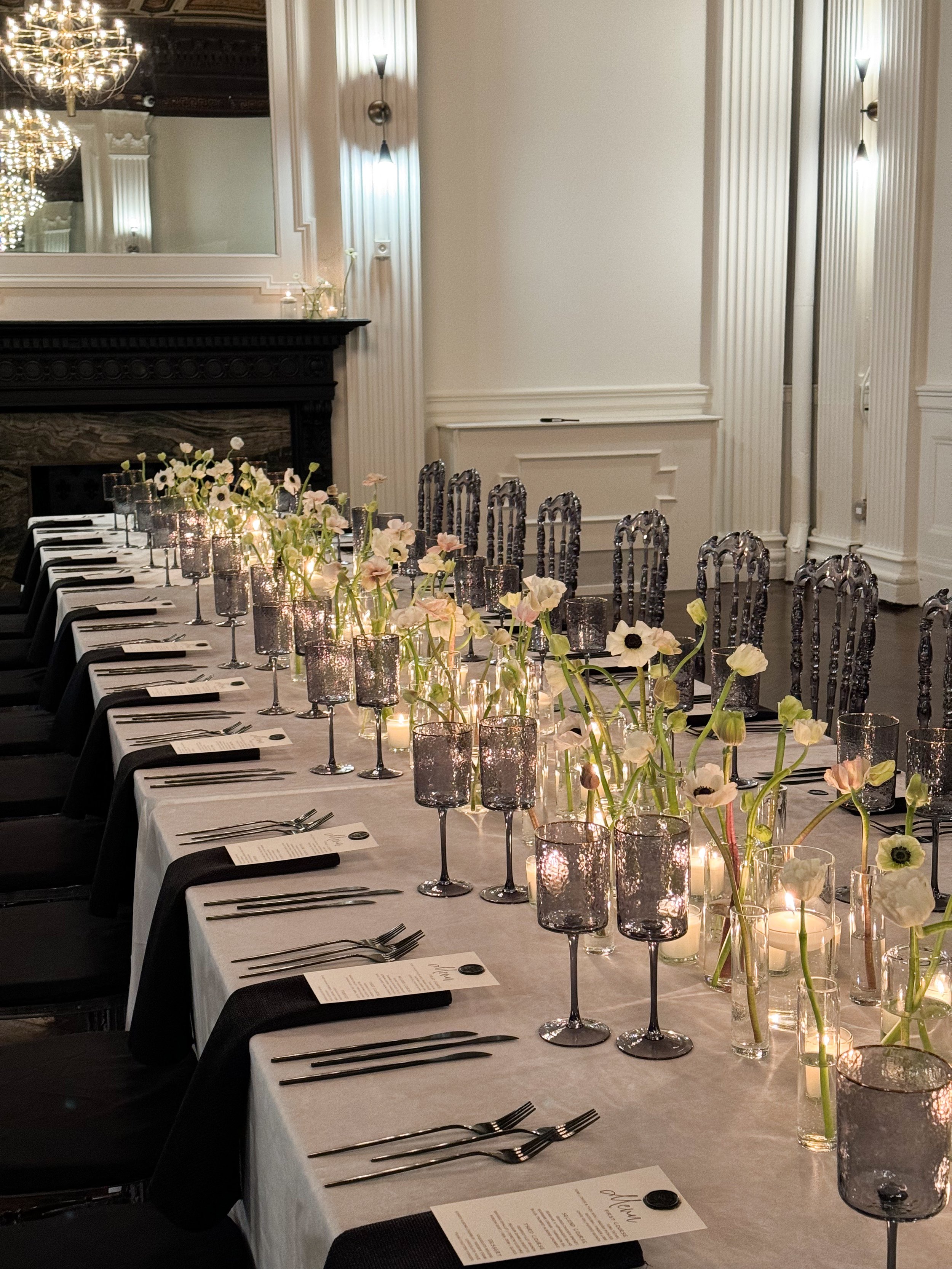 Elegant dining table set for a formal event decorated with single stem of anemone bud vases
