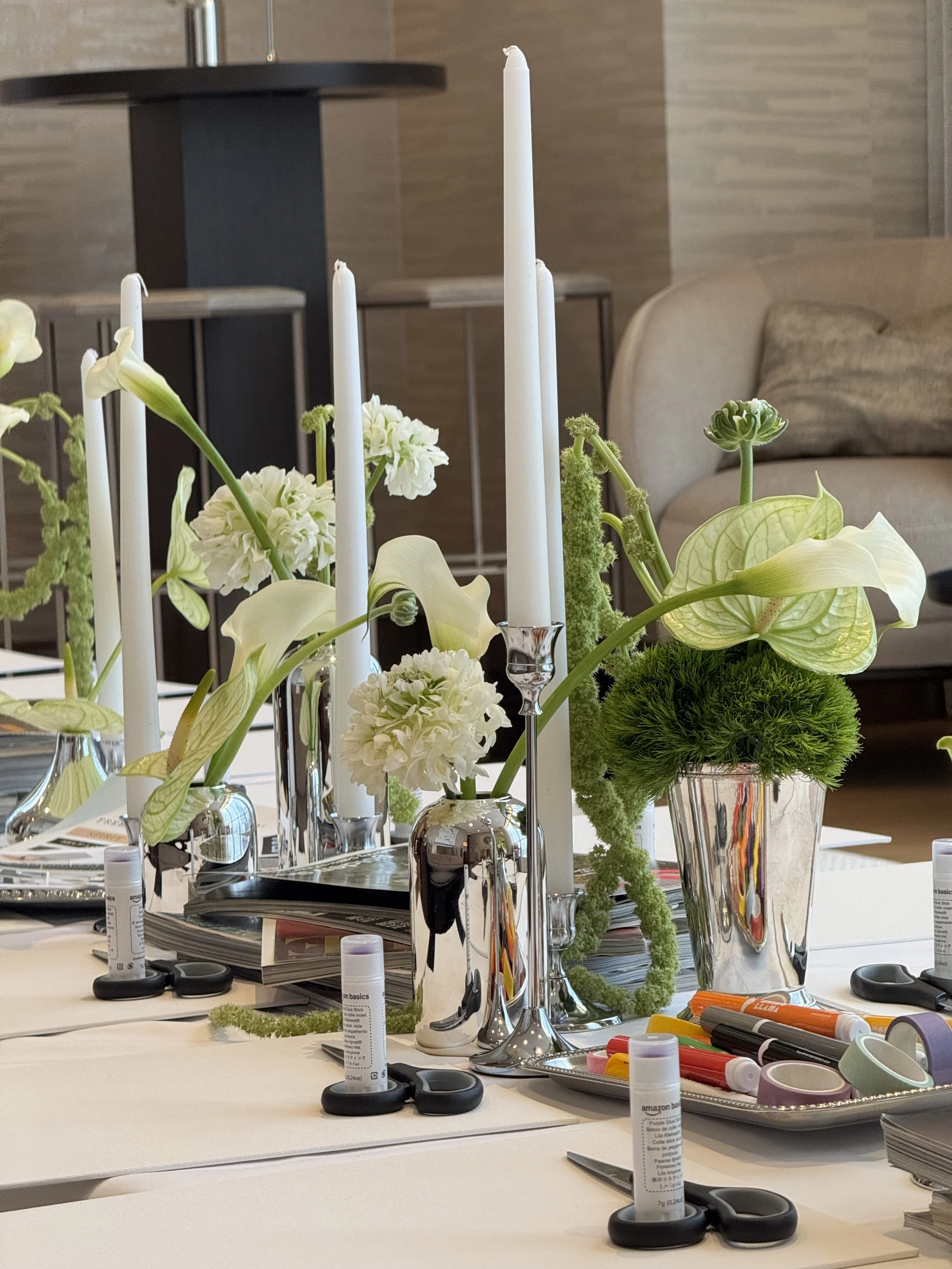 Tablescape created with chrome accents: bud vases and candle holders. Bud vases filled with green and white modern florals: hanging amaranth, anthurium, calla lily, ranunculus.